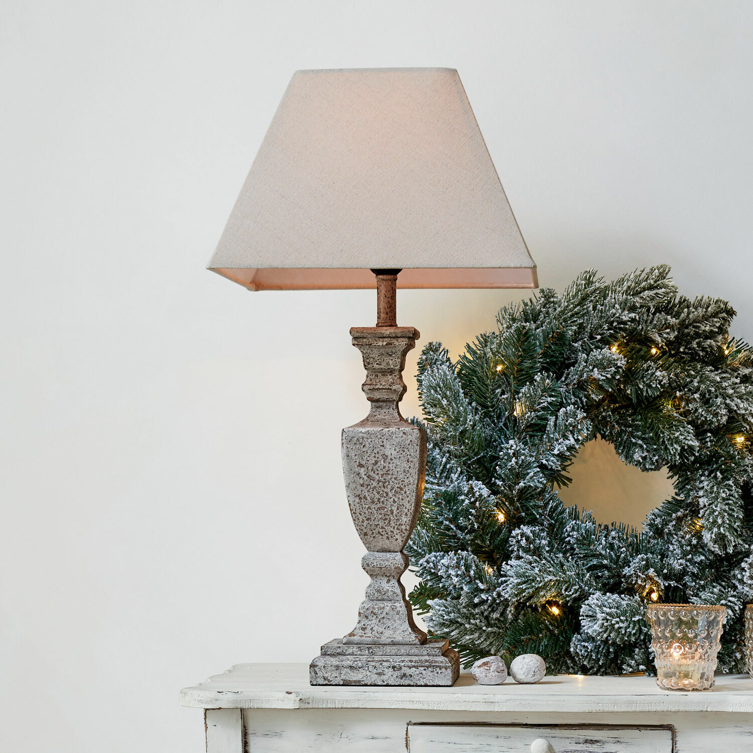 Lámpara de mesa Gorham Lámpara de mesa de piedra beige con pantalla junto a corona navideña verde con luces decorativas