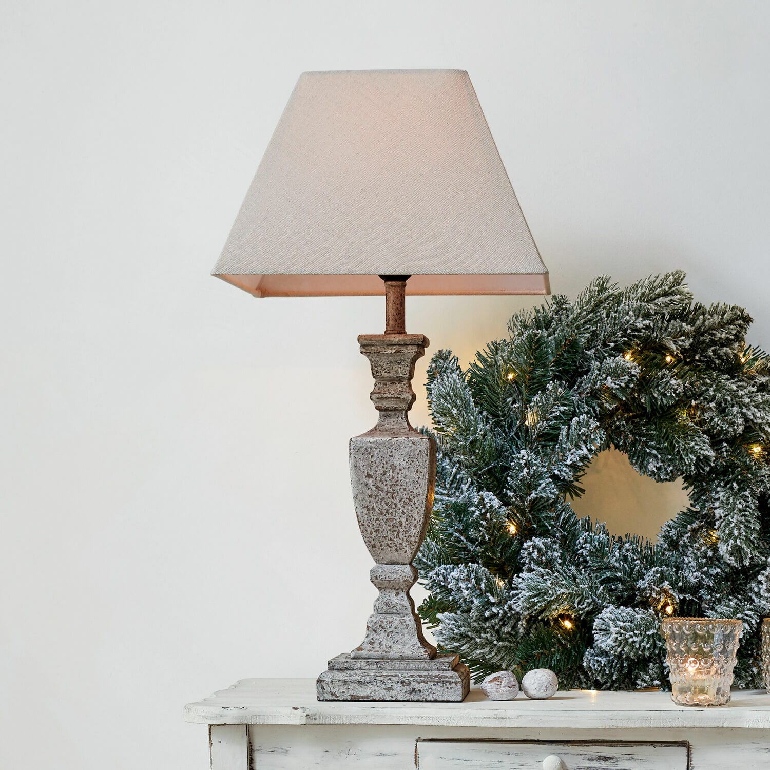Lámpara de mesa Gorham Lámpara de mesa de piedra beige con pantalla junto a corona navideña verde con luces decorativas