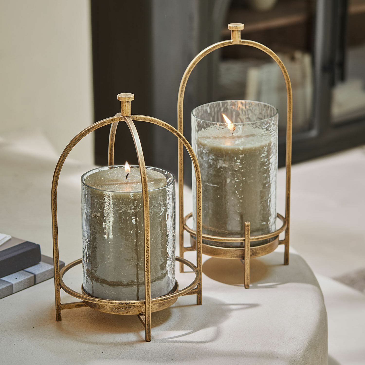 Set de 2 portavelas Biserre Dos portavelas de vidrio con estructura metálica dorada envejecida y velas grises decorativas