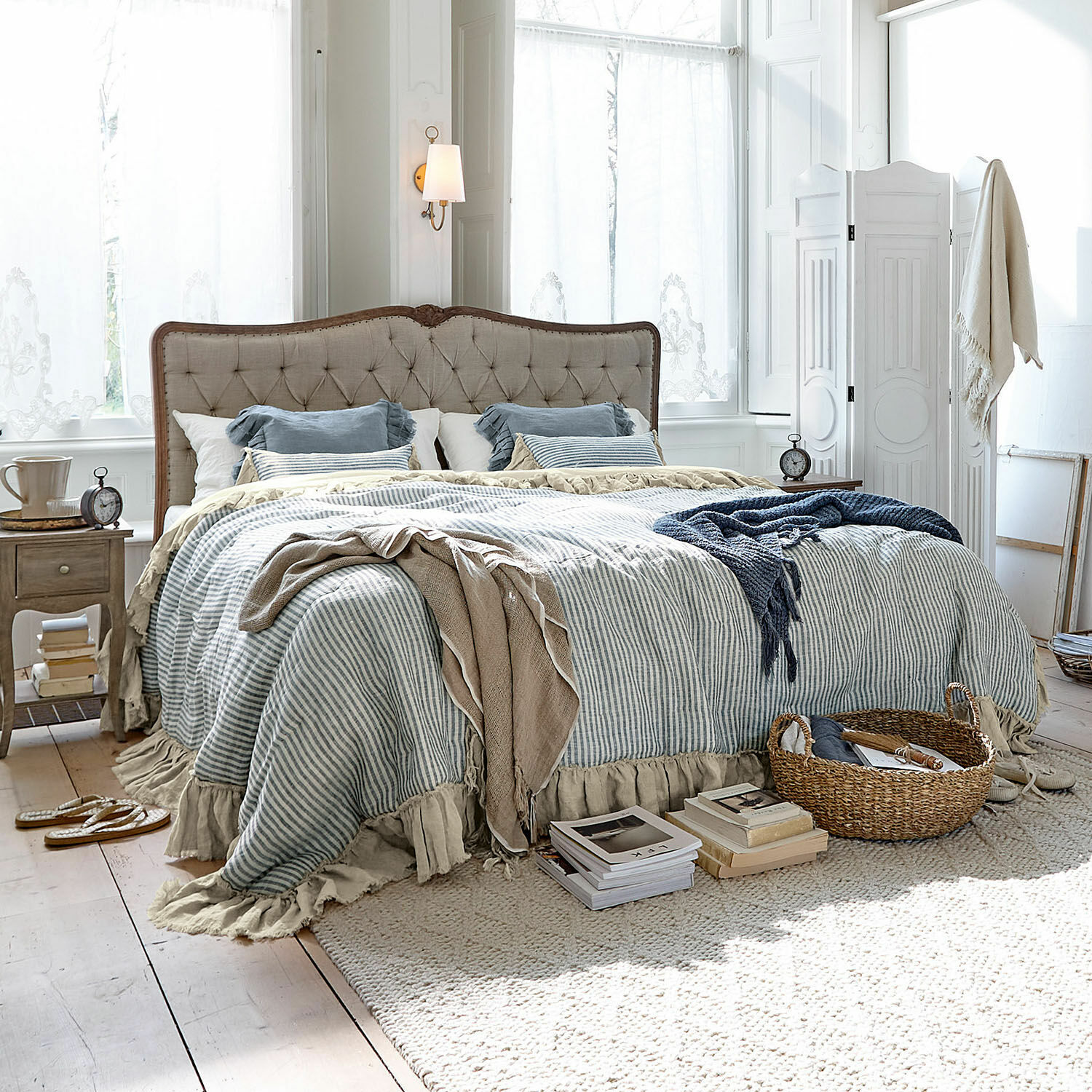 Colcha Alexane Dormitorio acogedor con cama de tela beige y ropa de cama a rayas azul y blanca