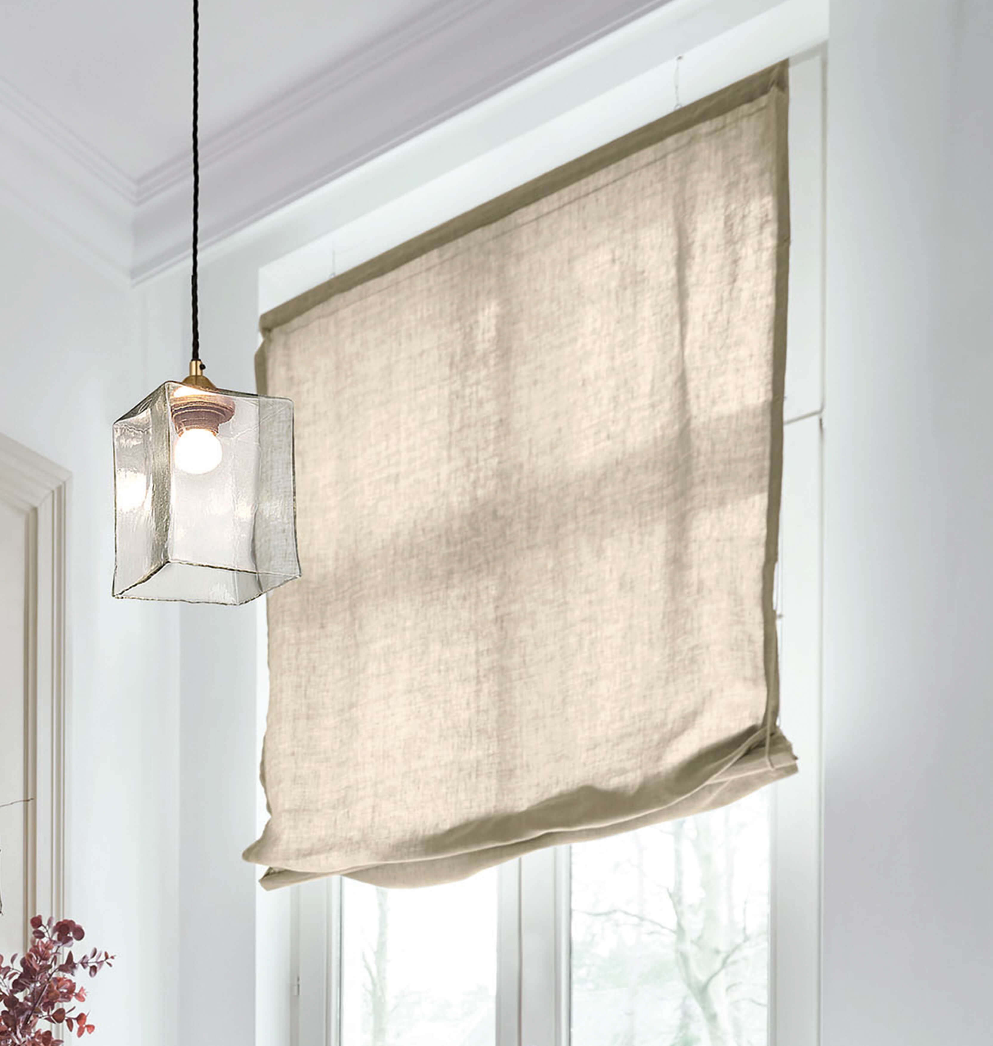 Estor romano beige de lino en habitación luminosa con lámpara colgante de vidrio transparente