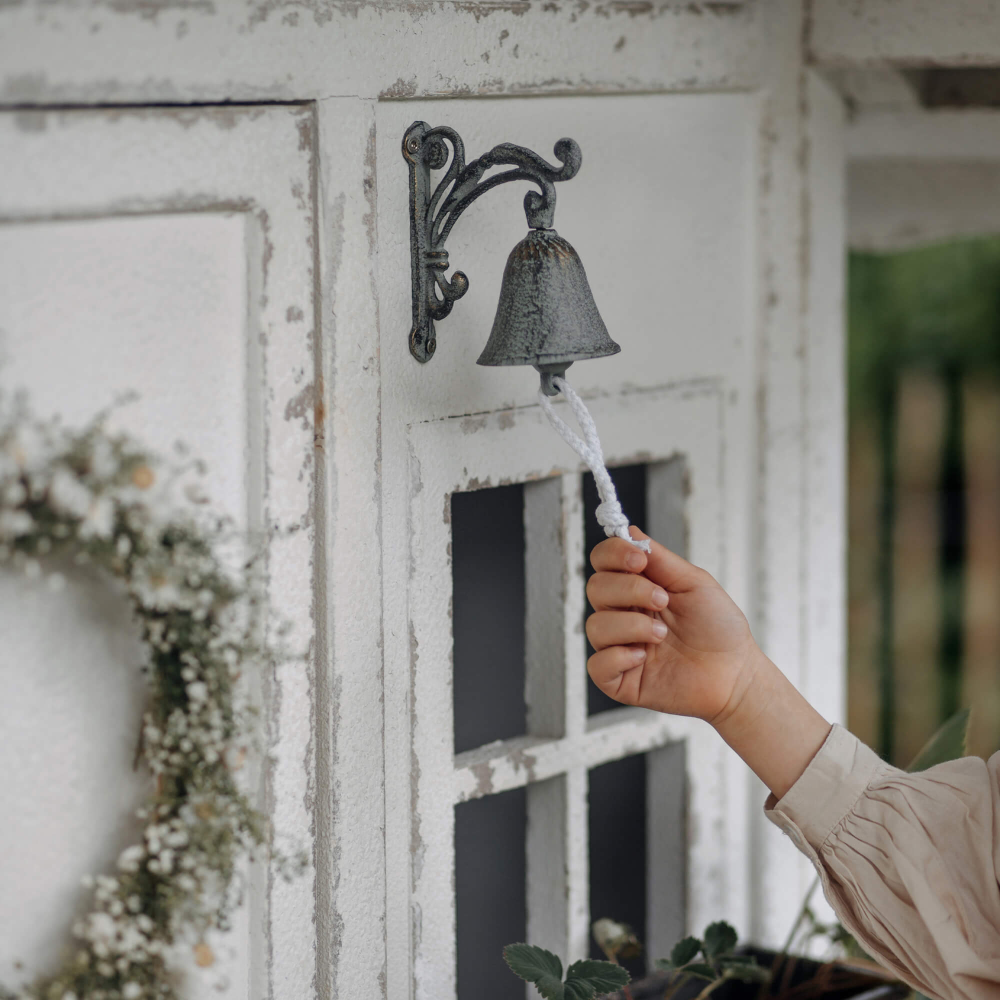 Campana metálica estilo vintage con cuerda blanca en pared exterior desgastada