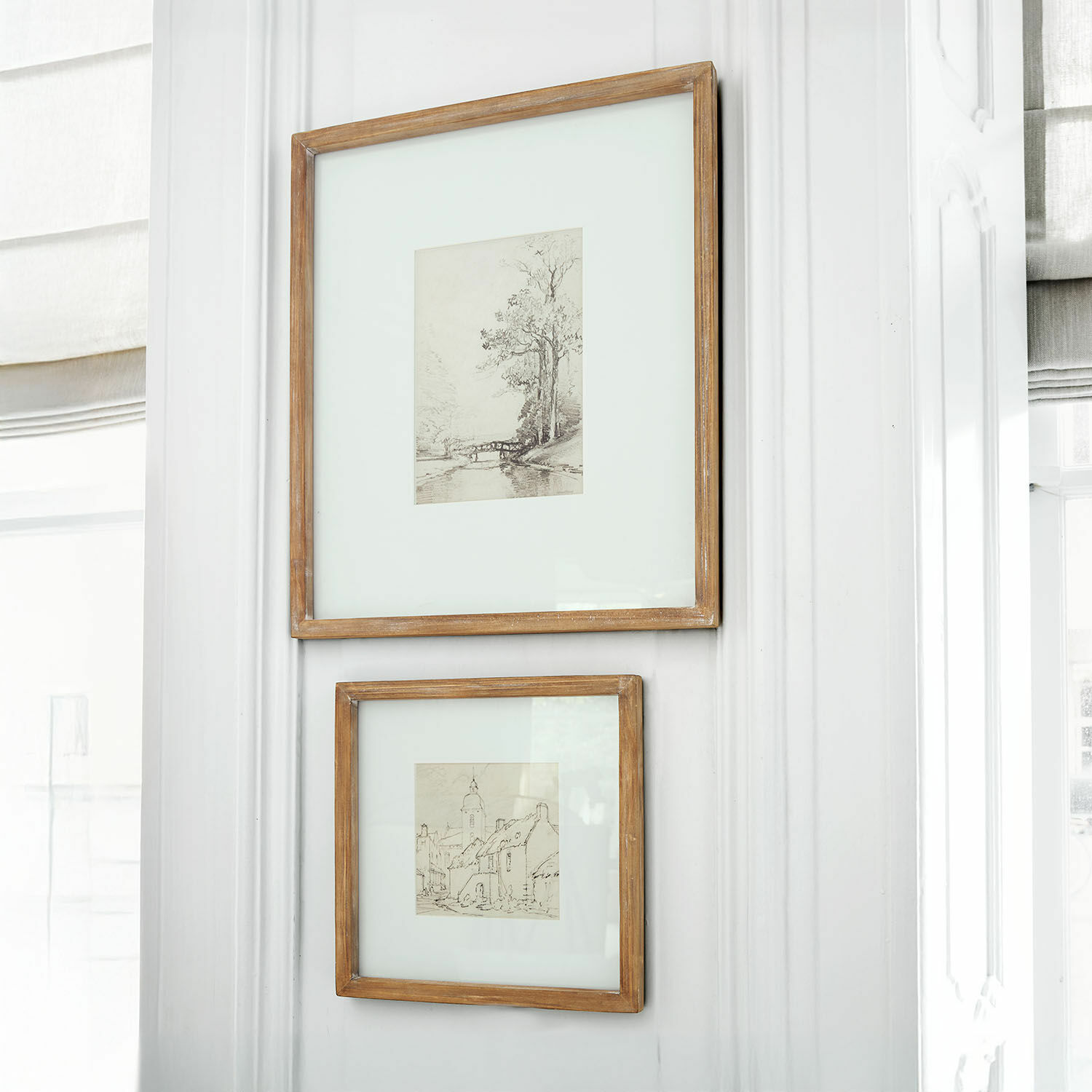Set de 2 cuadros Juvarel Dos marcos de madera rústica con dibujos de paisajes colgados en pared blanca luminosa