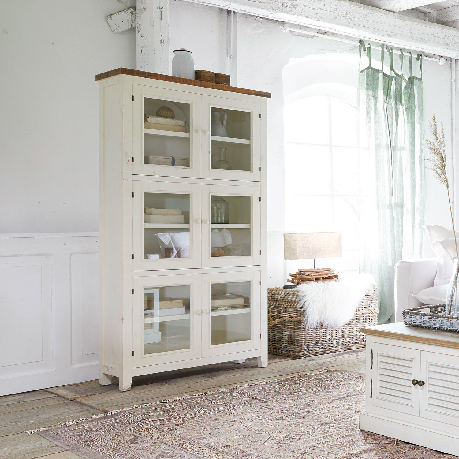 Armario Yukon Vitrina blanca de madera con puertas de cristal en salón luminoso con luz natural