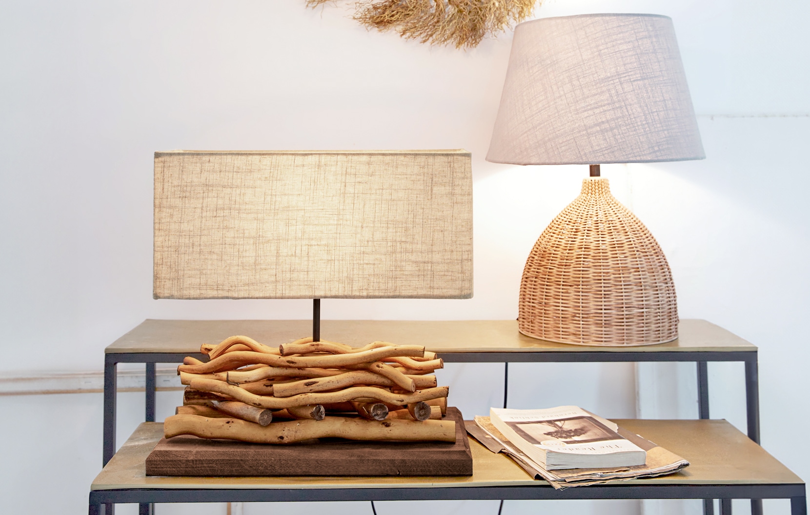 Dos lámparas de mesa de madera natural y mimbre con pantallas beige sobre mesa metálica