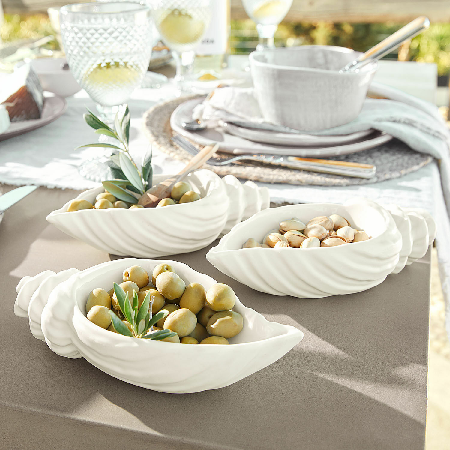 Set de 3 cuencos Portavin Cuencos de cerámica blanca con forma de concha con aceitunas y nueces sobre mesa de jardín
