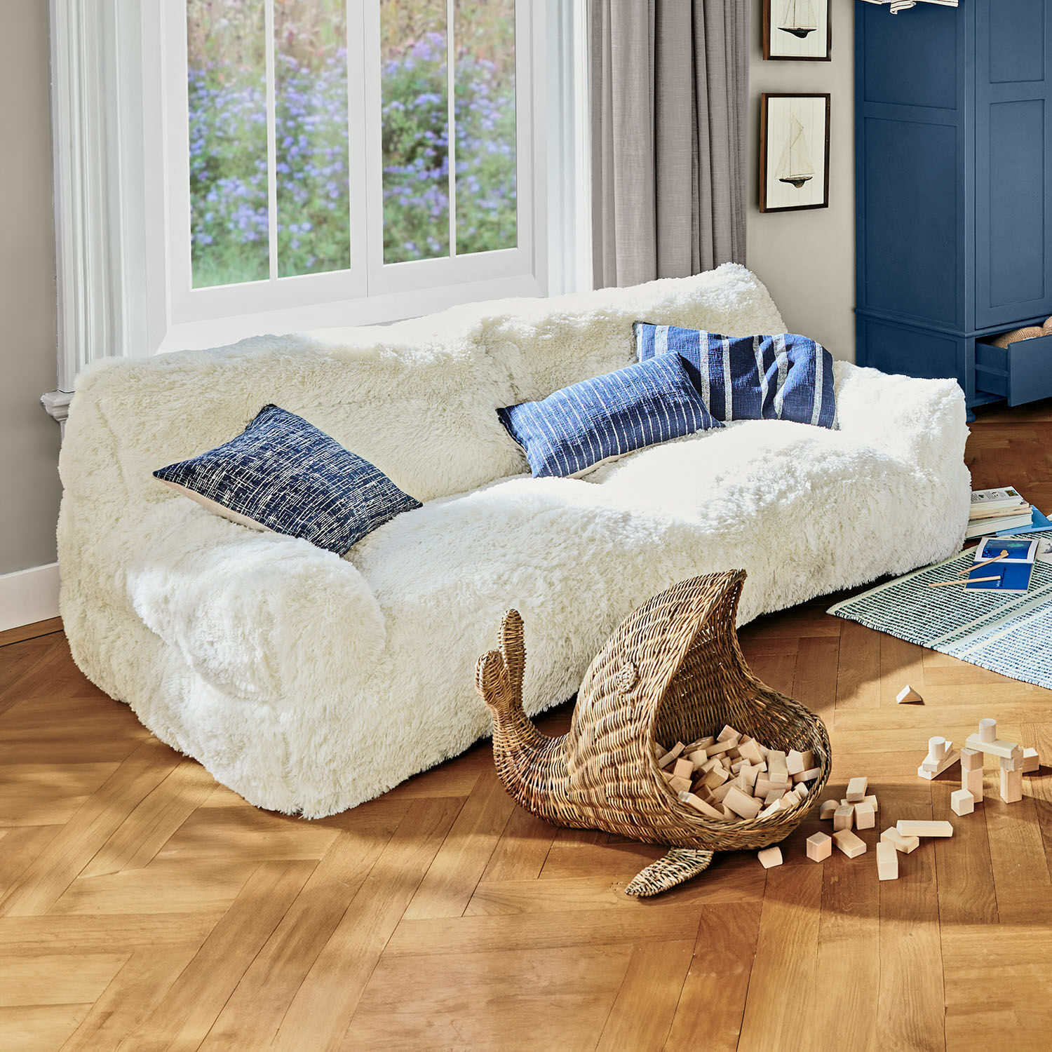 Sofá para niños Cerveteri Sofá blanco de felpa con cojines azules en sala luminosa con suelo de madera