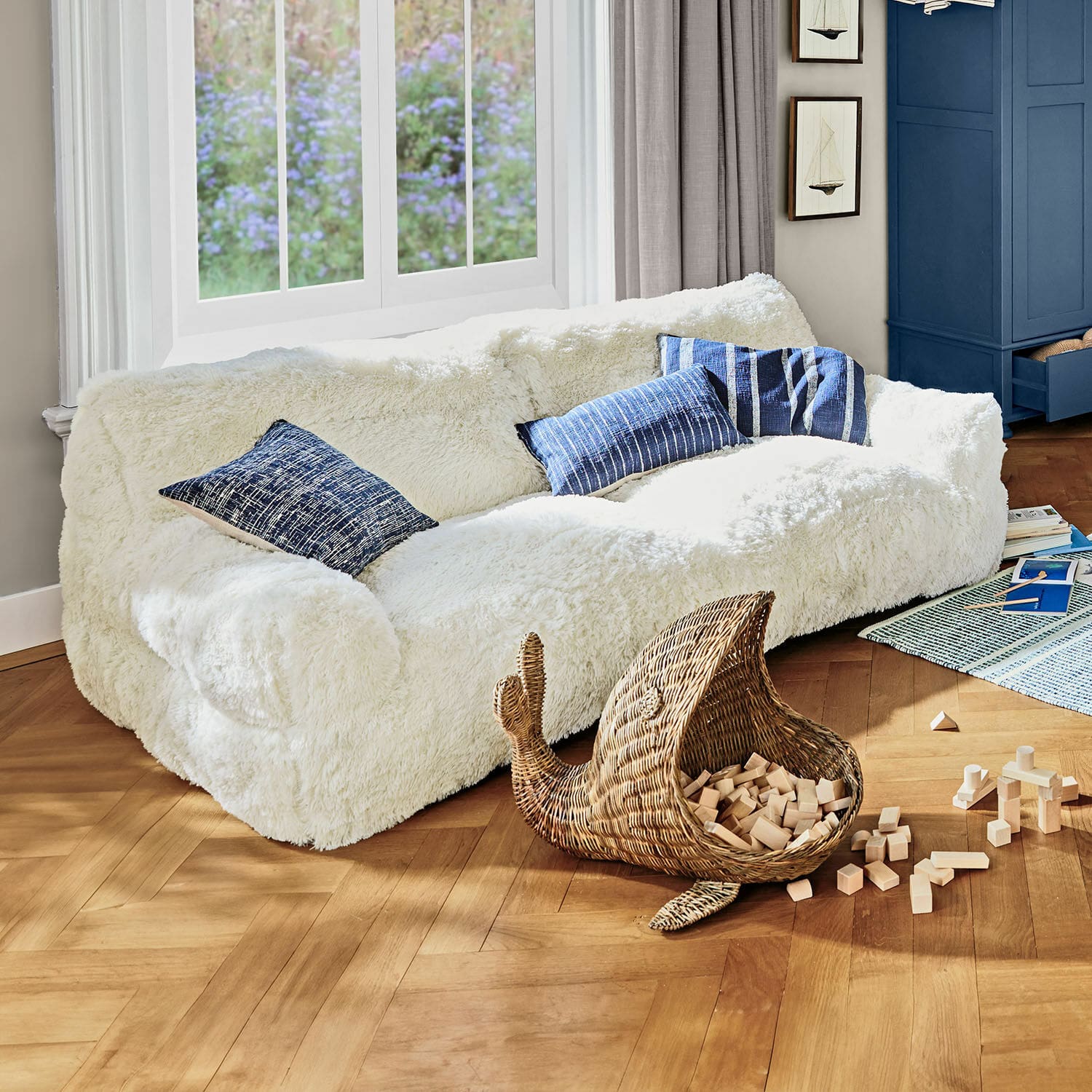 Sofá para niños Cerveteri Sofá blanco de felpa con cojines azules en sala luminosa con suelo de madera