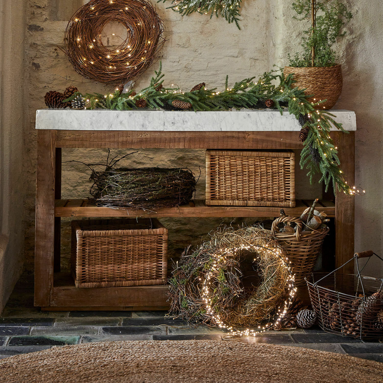 Mesa rústica de madera con encimera de mármol y decoración navideña con ramas y luces LED