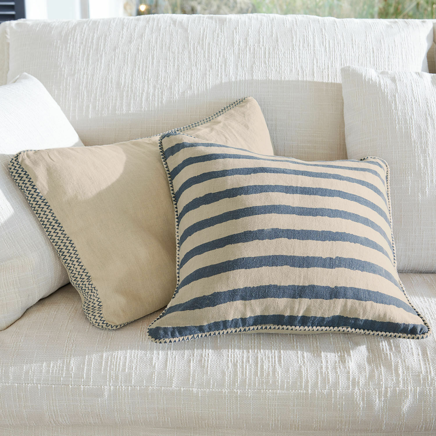 Set de 2 fundas de cojín Alarindor Cojines decorativos de algodón beige y a rayas sobre sofá blanco para sala de estar