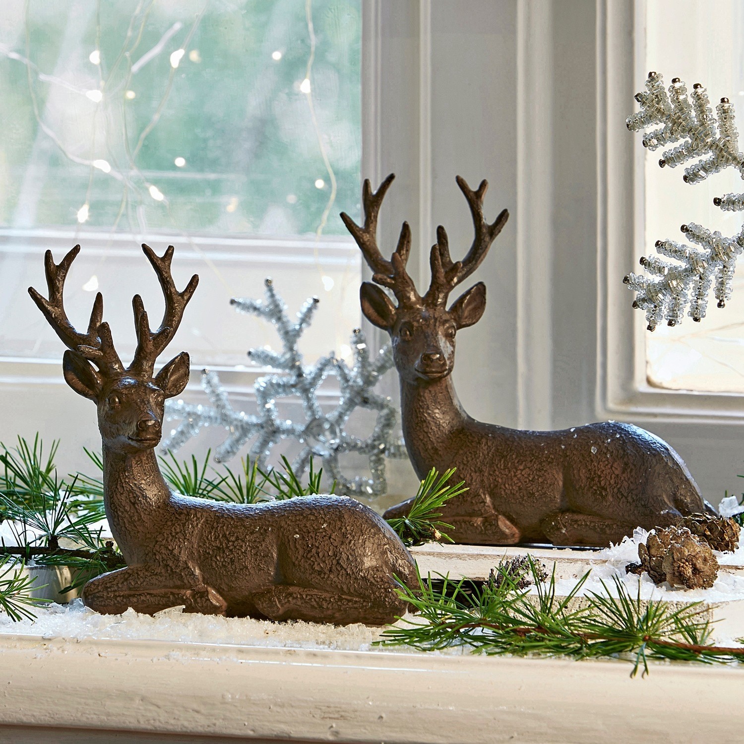 Set de 2 ciervos Janville Decoraciones de renos marrones de plástico en alféizar con ramas verdes y nieve artificial