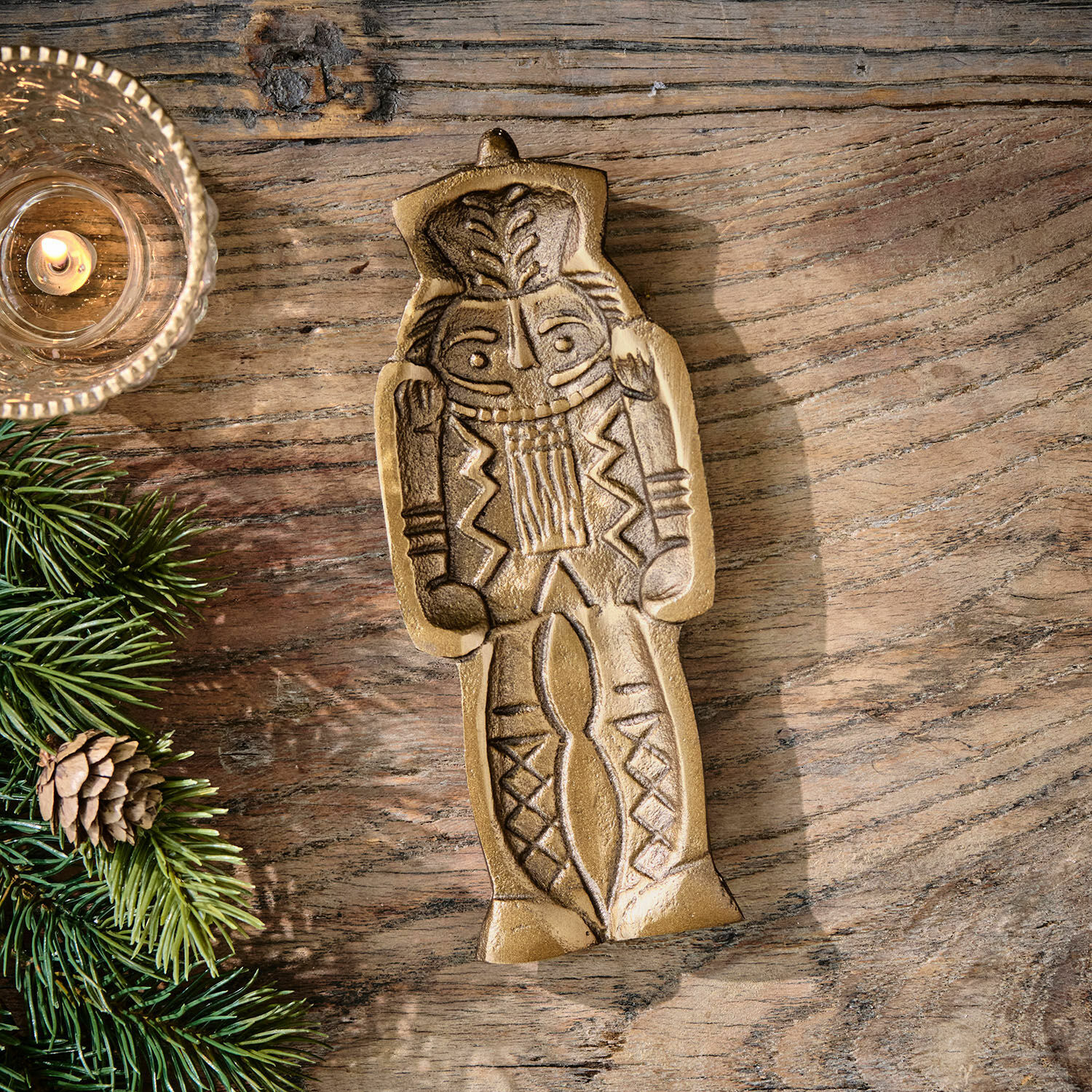 Cuenco decorativo Zarilith Figura decorativa de metal dorado sobre mesa de madera con rama de abeto y vela encendida