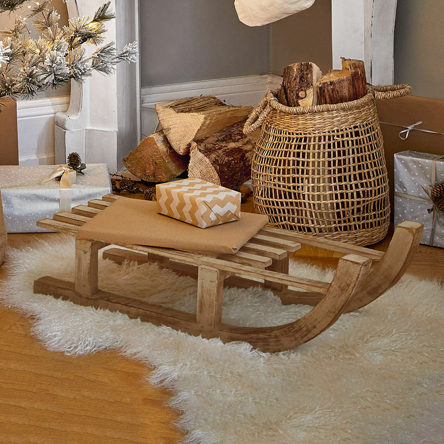 Trineo decorativo FSC®-100% Hoekstra Trineo decorativo de madera sobre alfombra blanca de piel sintética con regalos y cesta de leña