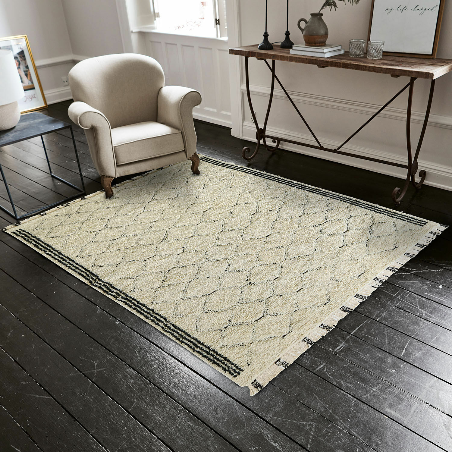 Alfombra Himesto Alfombra beige con patrón geométrico y flecos sobre suelo de madera oscura en sala de estar