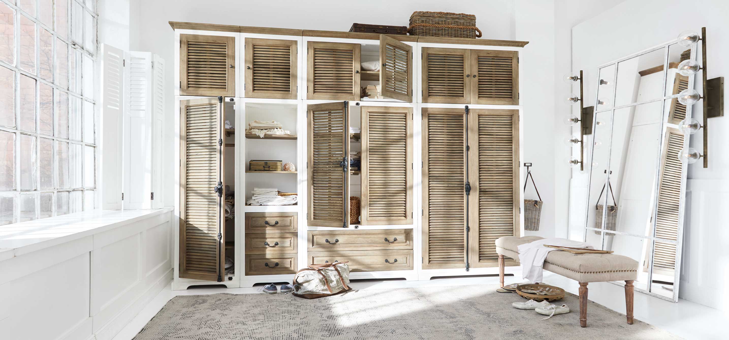 Gran armario de madera con marco blanco, puertas de persiana y cajones en habitación luminosa