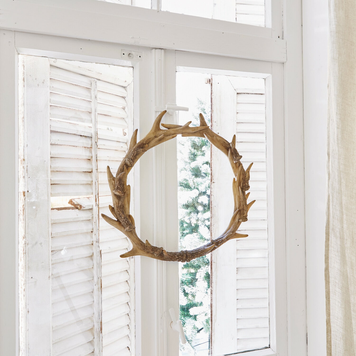 Corona Marcelle Corona decorativa de madera en forma de asta en ventana blanca con velas y piñas