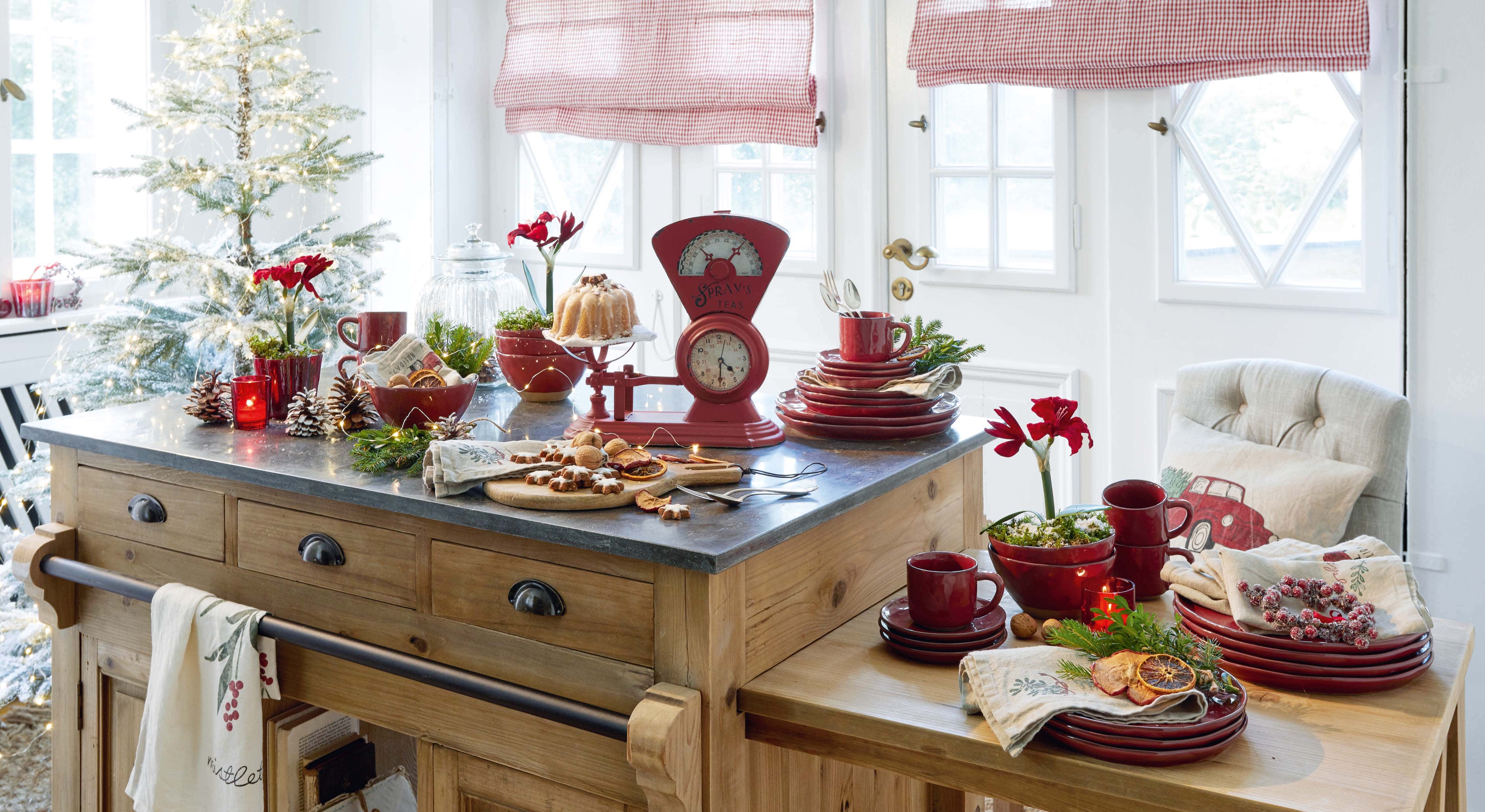 Cocina con isla de madera, vajilla cerámica roja y decoración navideña con luces LED