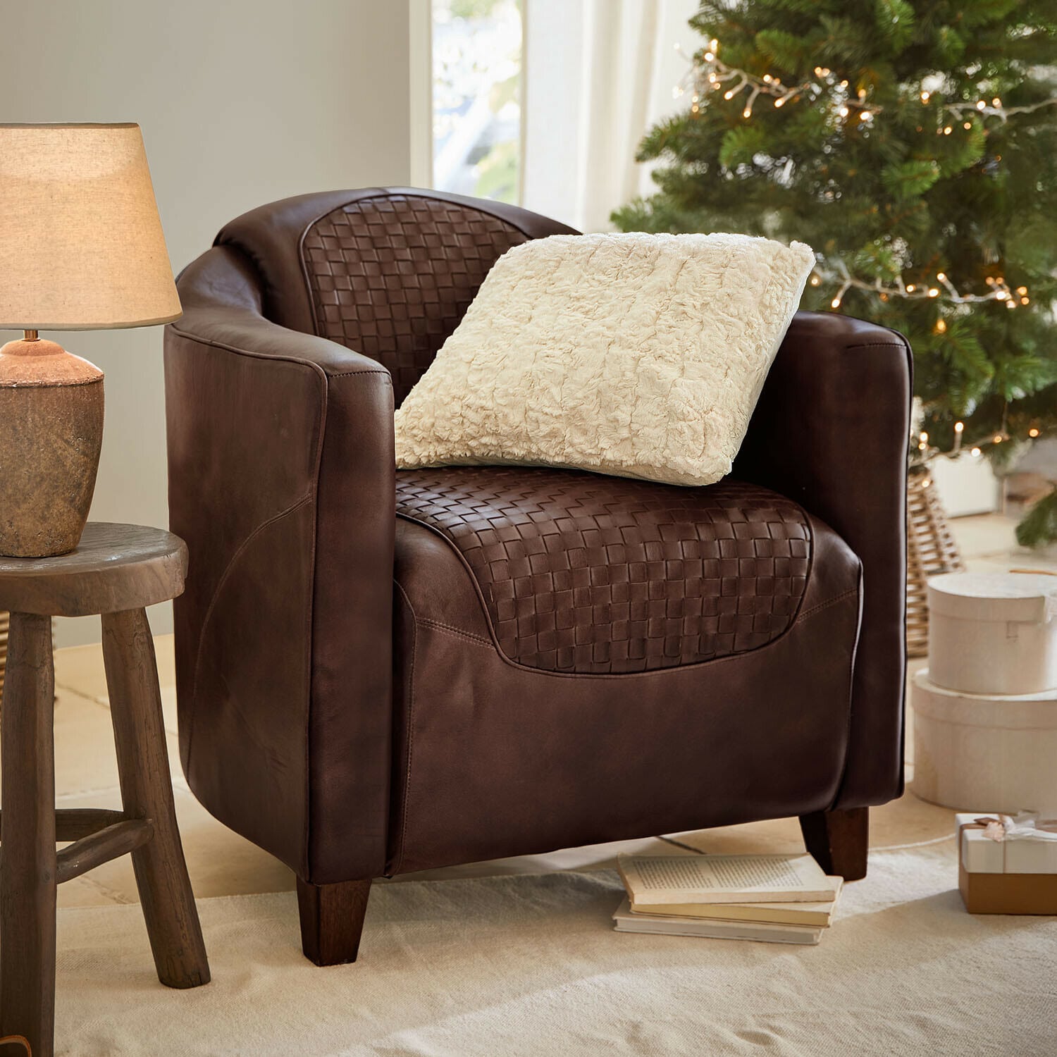 Sillón Westerdales Sillón marrón de cuero trenzado con cojín crema, ambiente acogedor con lámpara y árbol de Navidad