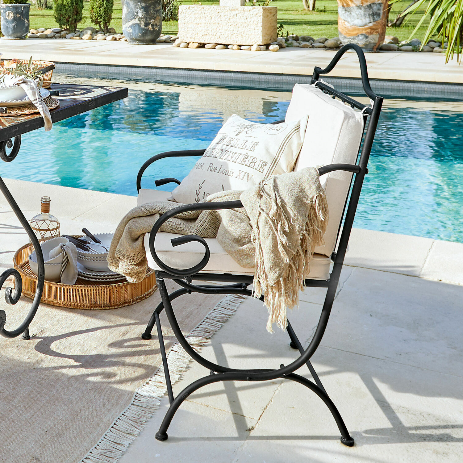 Silla Avanton Sillón de jardín de metal negro con cojín crema y manta beige junto a la piscina, muebles de exterior