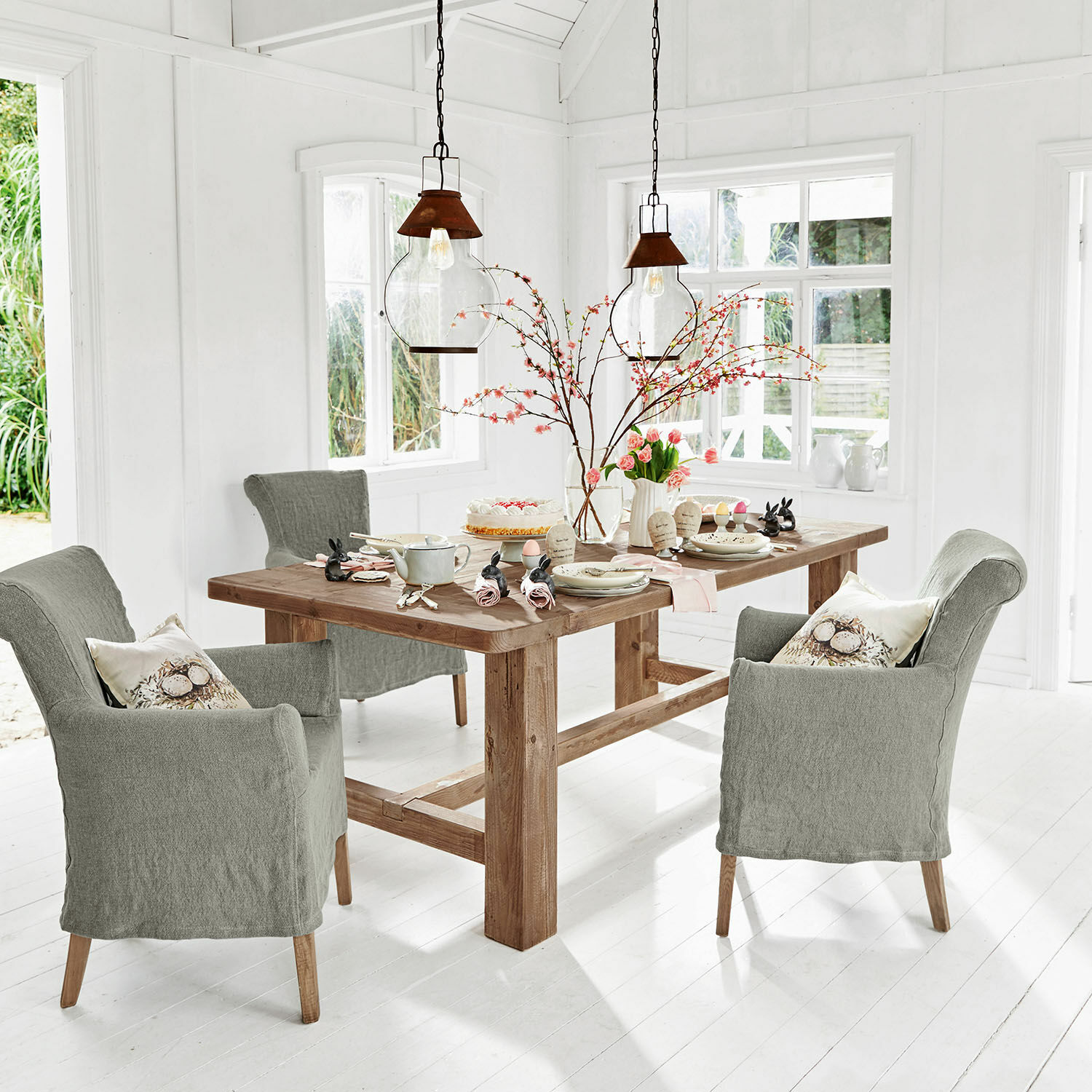 Mesa Oteley Comedor con mesa de madera y sillas tapizadas grises en un interior moderno y luminoso