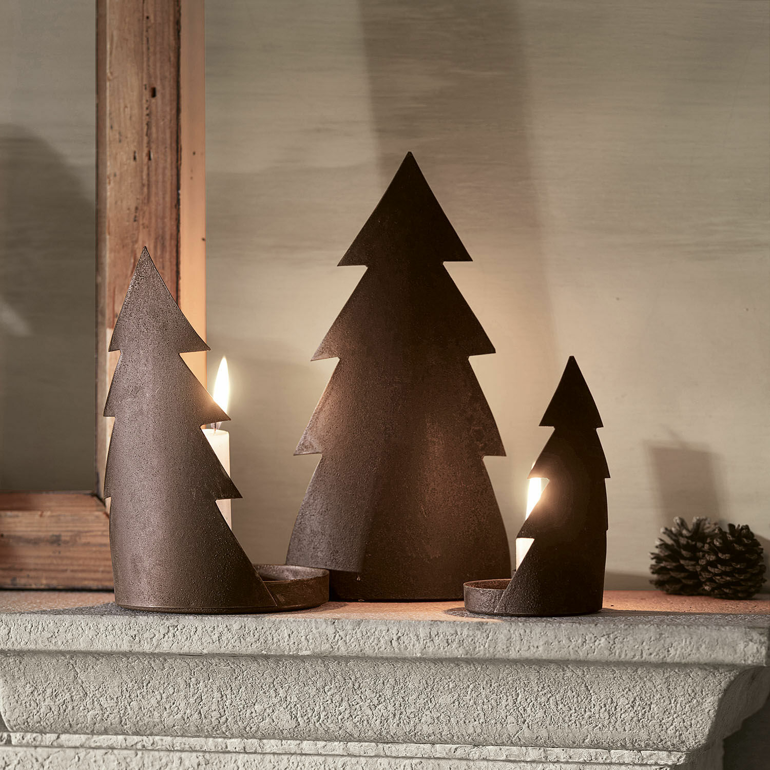 Juego de 3 candelabros Ageville Conjunto de tres candelabros de metal oxidado con forma de árbol de Navidad sobre la repisa de la chimenea