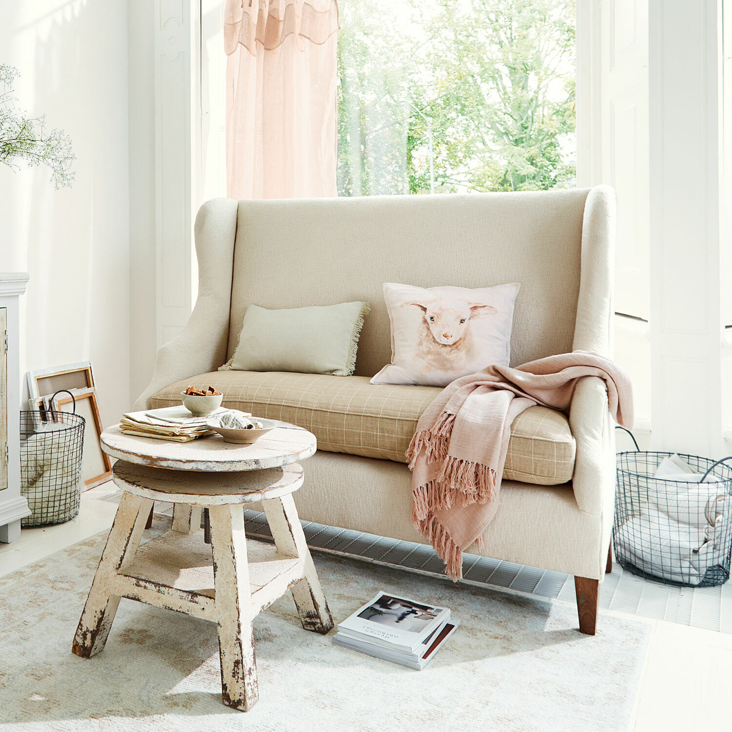 Sofa Ombra Sofá beige de tela con cojín de cordero y mesa de centro rústica de madera en sala luminosa
