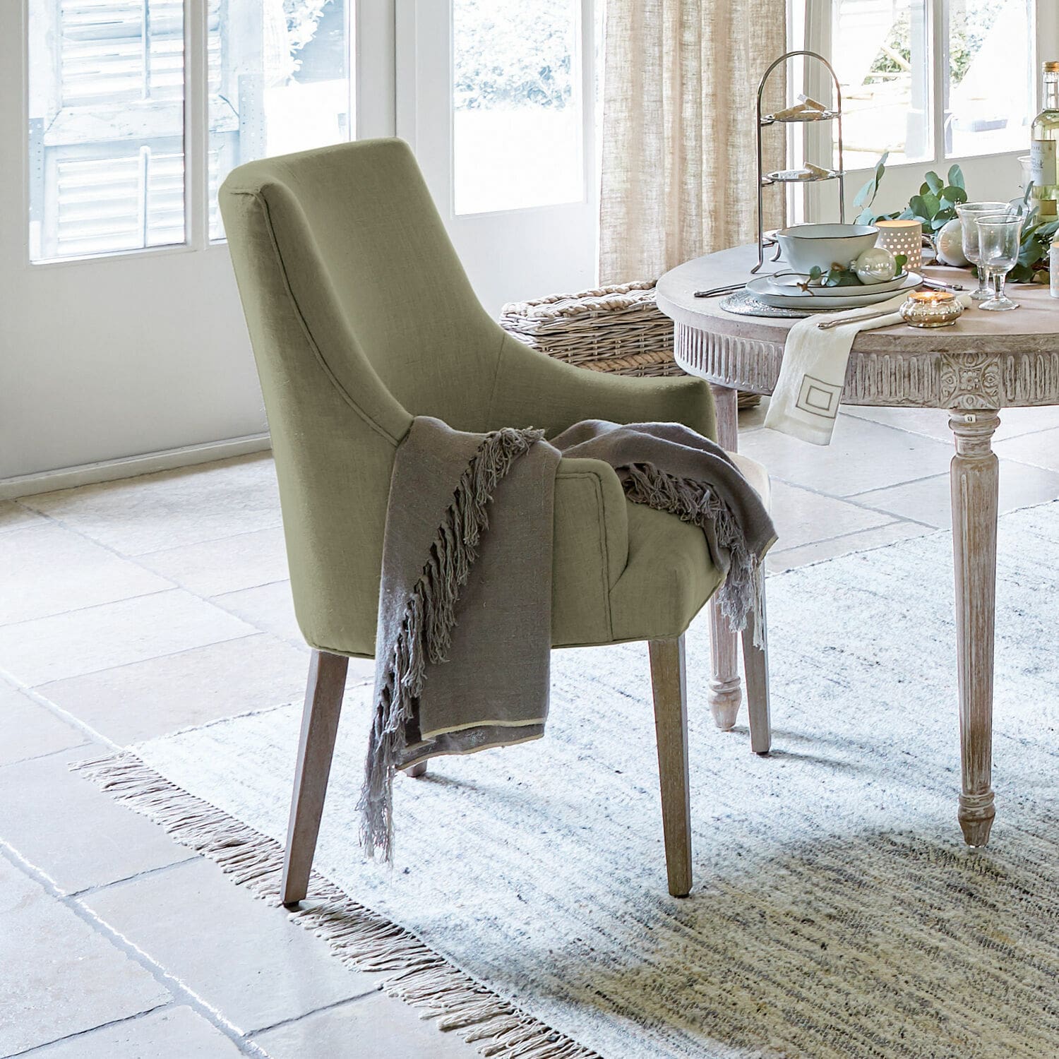 Silla Hyeres Silla tapizada verde con patas de madera y manta gris en sala luminosa con alfombra