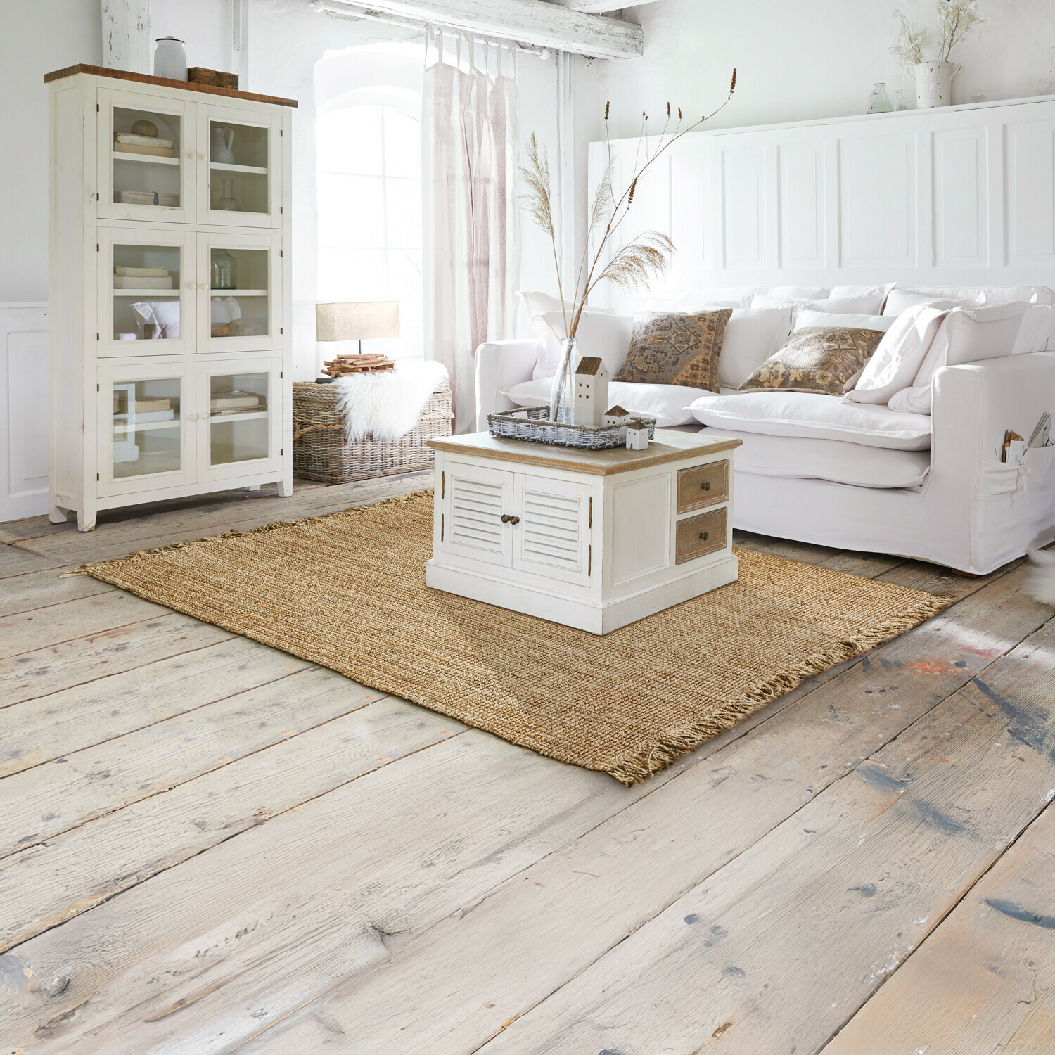 Alfombra Hermitage Sala luminosa con sofá blanco, mueble de madera clara y alfombra natural de yute en estilo rústico
