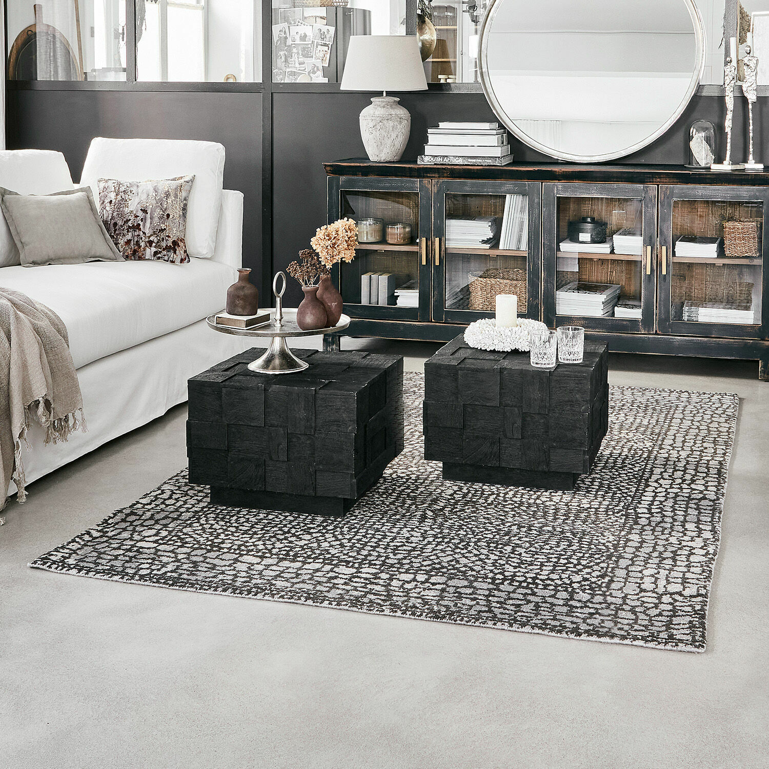Alfombra Vermont Salón moderno con sofá blanco y mesas de centro negras de madera sobre alfombra con patrón