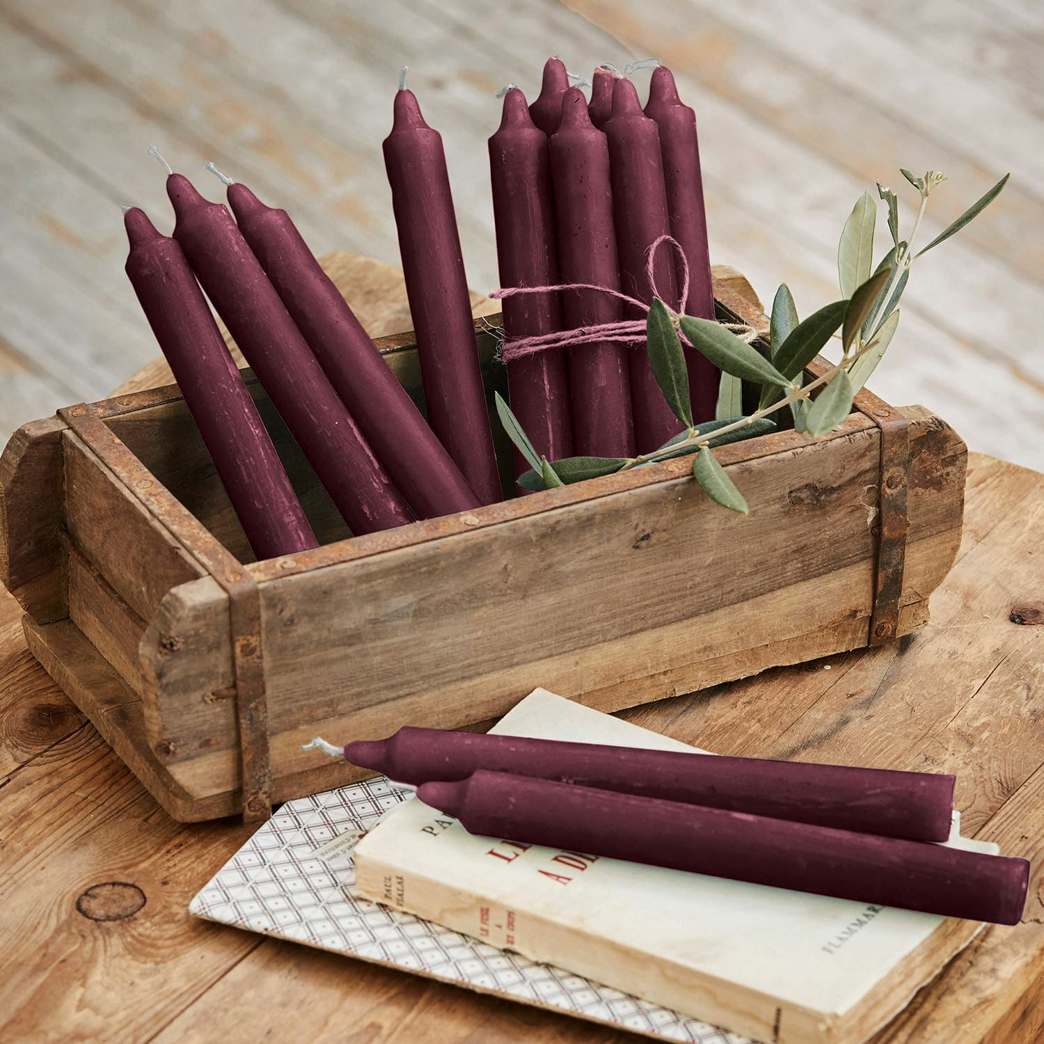 Set de 12 velas Bauceau Conjunto de velas de cera burdeos en caja de madera sobre mesa rústica