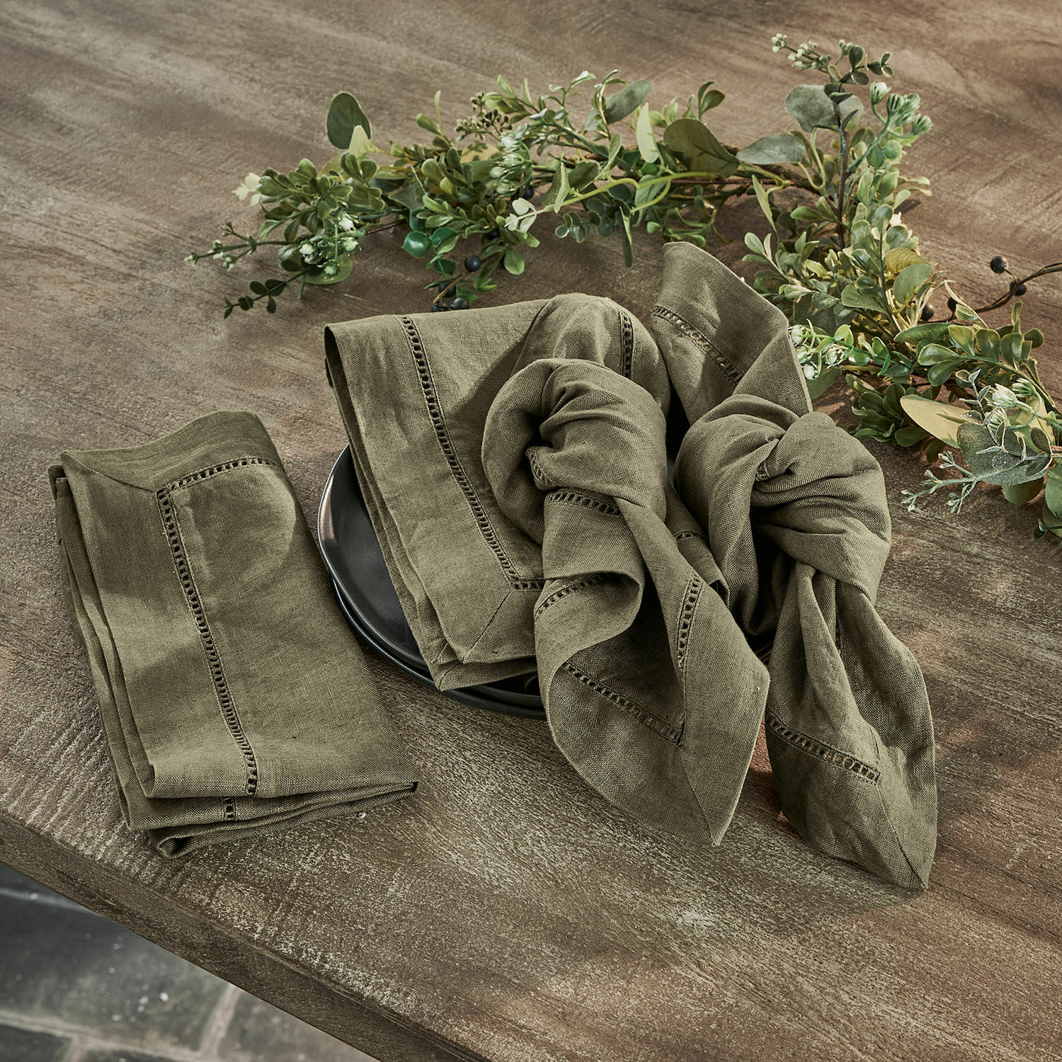 Set de 4 servilletas Covent Garden Juego de servilletas de lino verde con costura decorativa sobre mesa de madera con decoración vegetal
