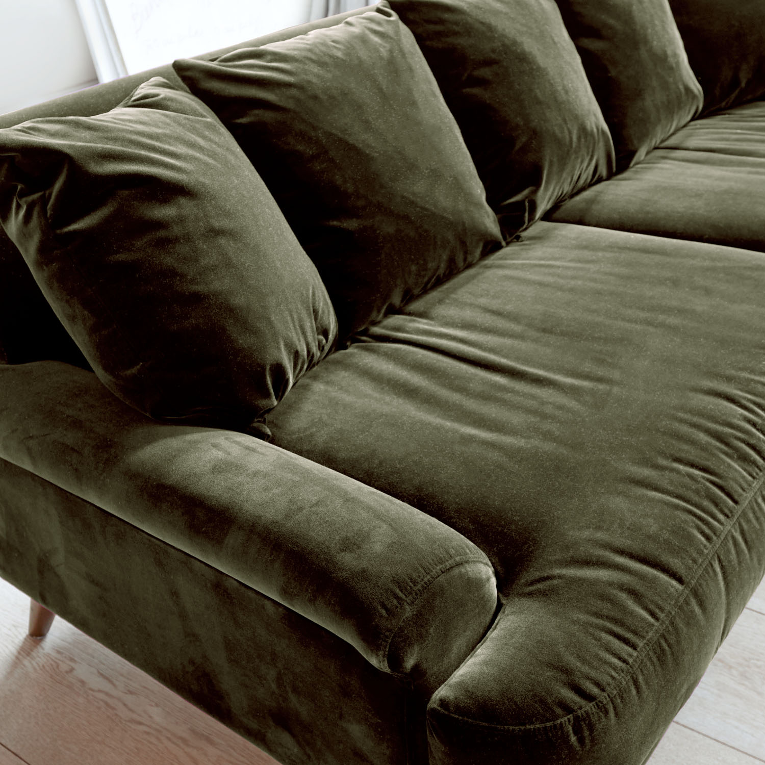 Sofá verde de terciopelo con cojines suaves y reposabrazos cómodos para salón