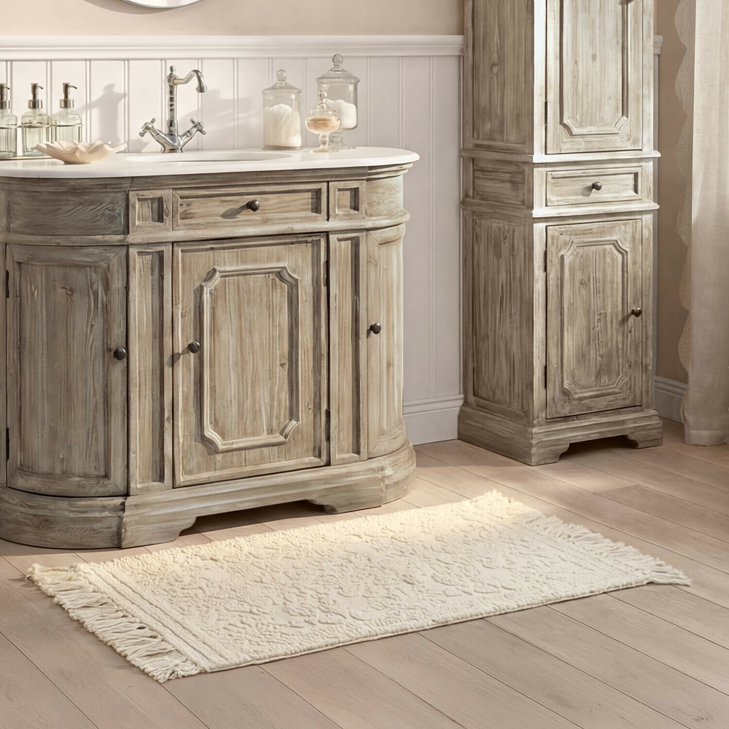Vase 2er Set Dolcin Alfombra de baño crema con flecos sobre suelo de madera clara junto a muebles de pino