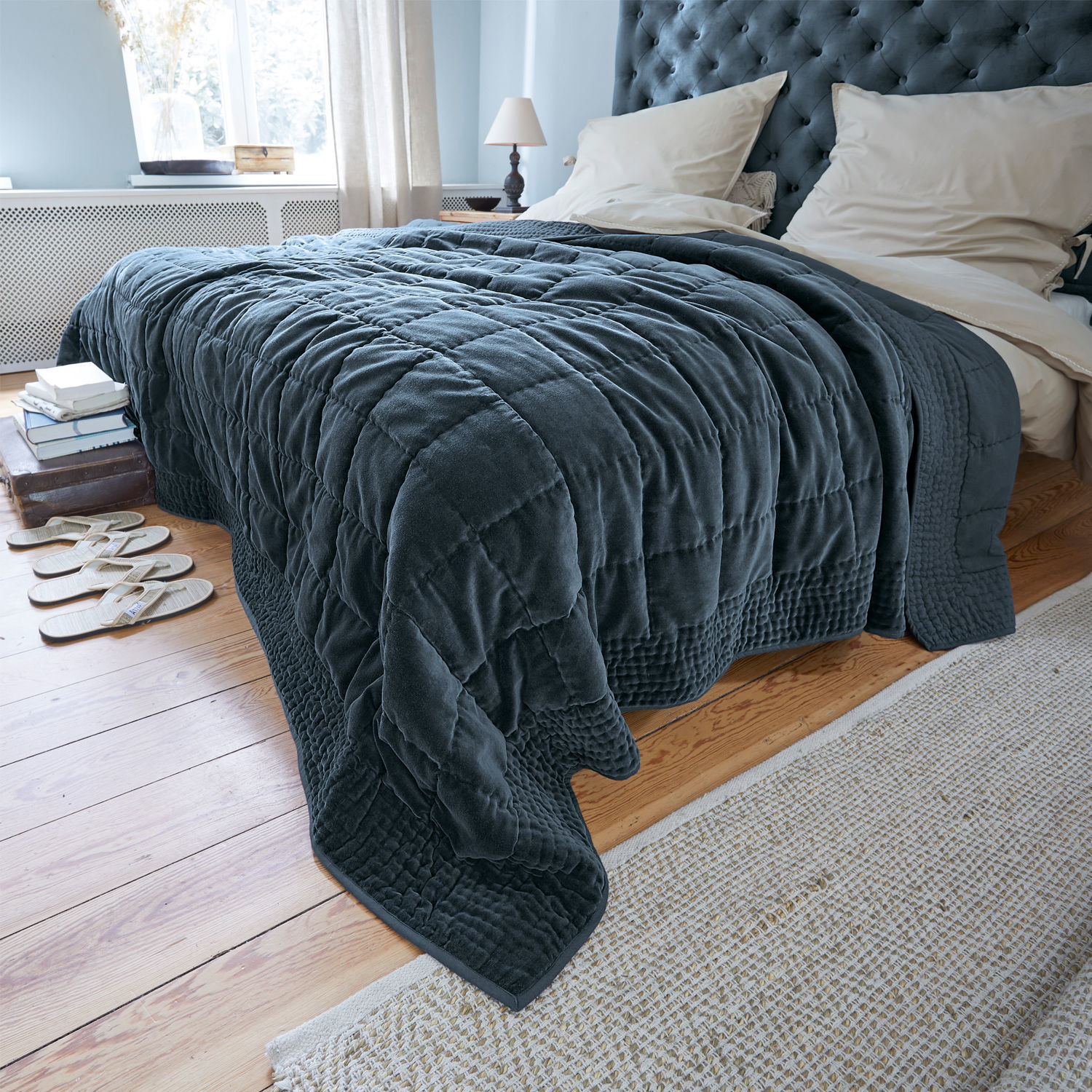 Colcha Arasta Manta acolchada azul marino de material suave sobre cama en dormitorio claro con suelo de madera