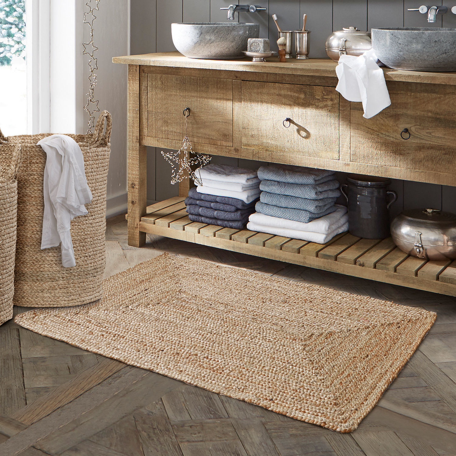 Alfombrilla de baño Busselton Alfombra de baño de yute natural beige sobre suelo de madera con cesta de ropa tejida