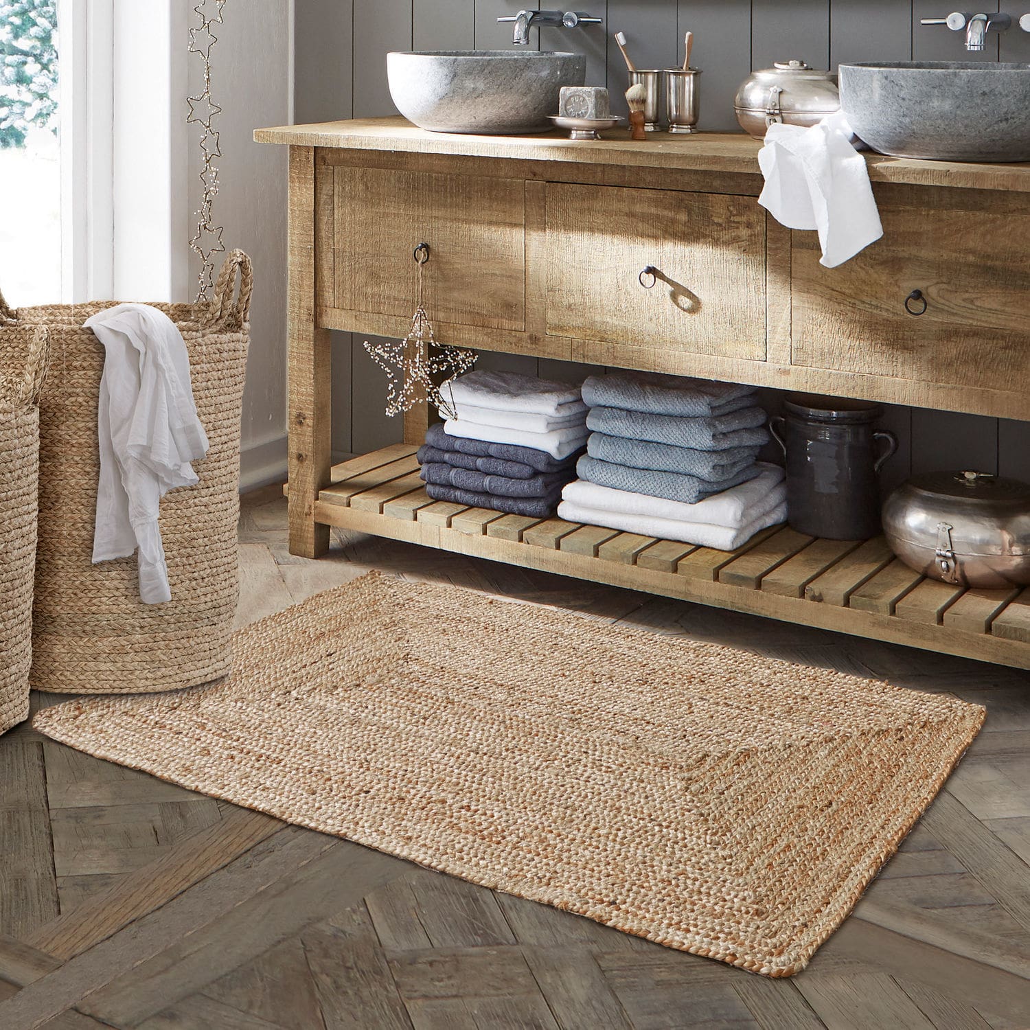 Alfombrilla de baño Busselton Alfombra de baño de yute natural beige sobre suelo de madera con cesta de ropa tejida