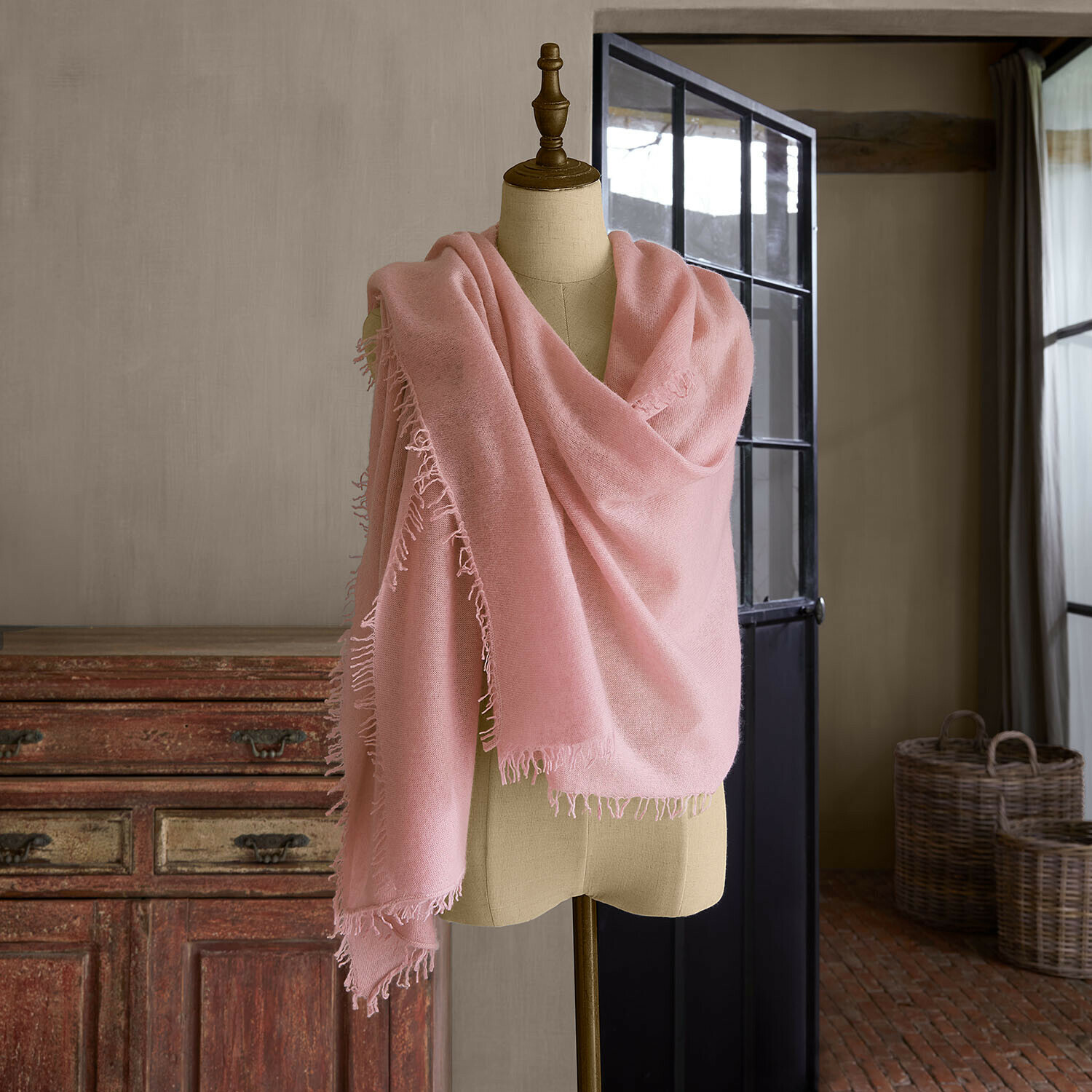 Chal Ulviane Chal rosa con flecos sobre maniquí en interior rústico, tejido suave para días frescos