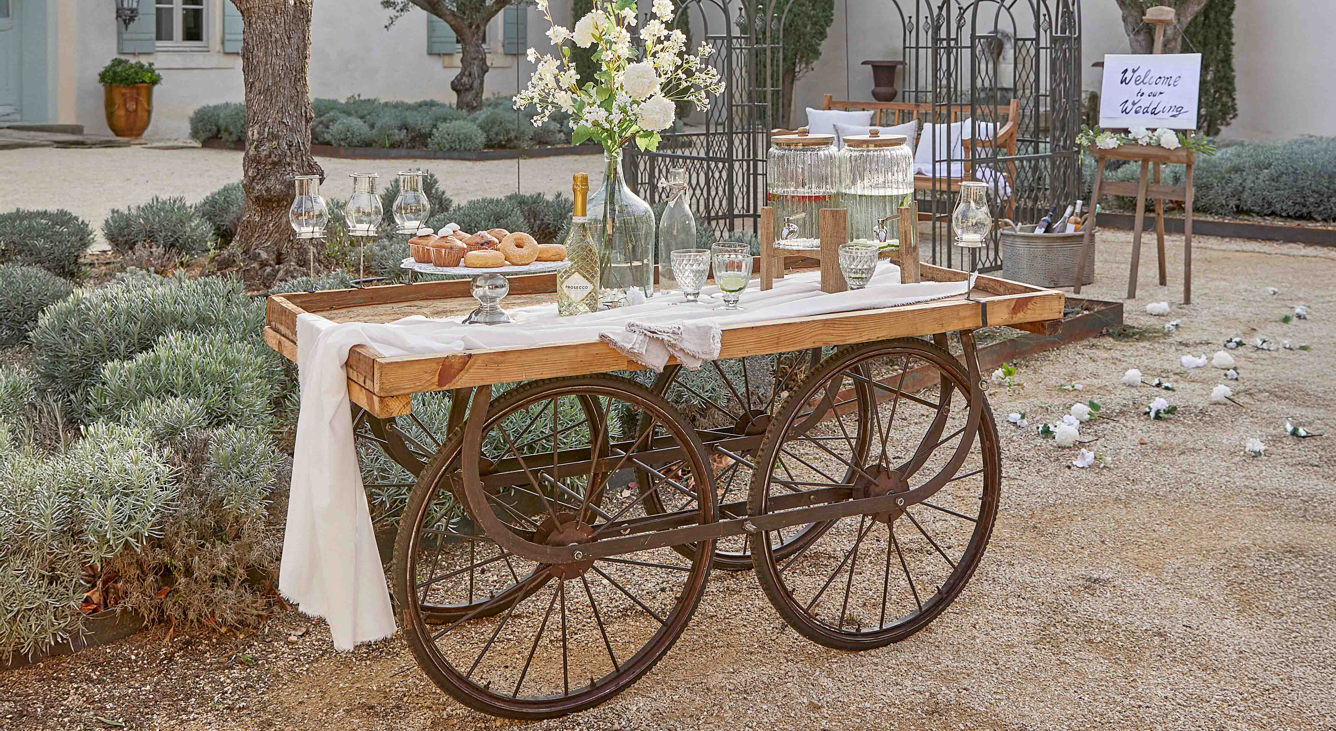 Carro de madera con ruedas metálicas decorado para boda con flores y bebidas