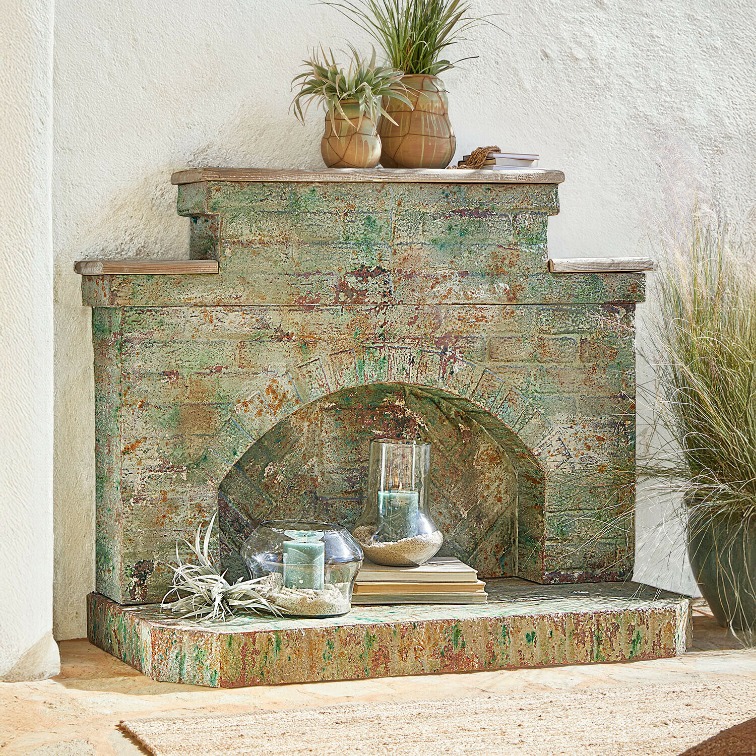 Consola de chimenea Kestonbury Chimenea decorativa de metal envejecido en tonos verdes y óxido con velas y plantas