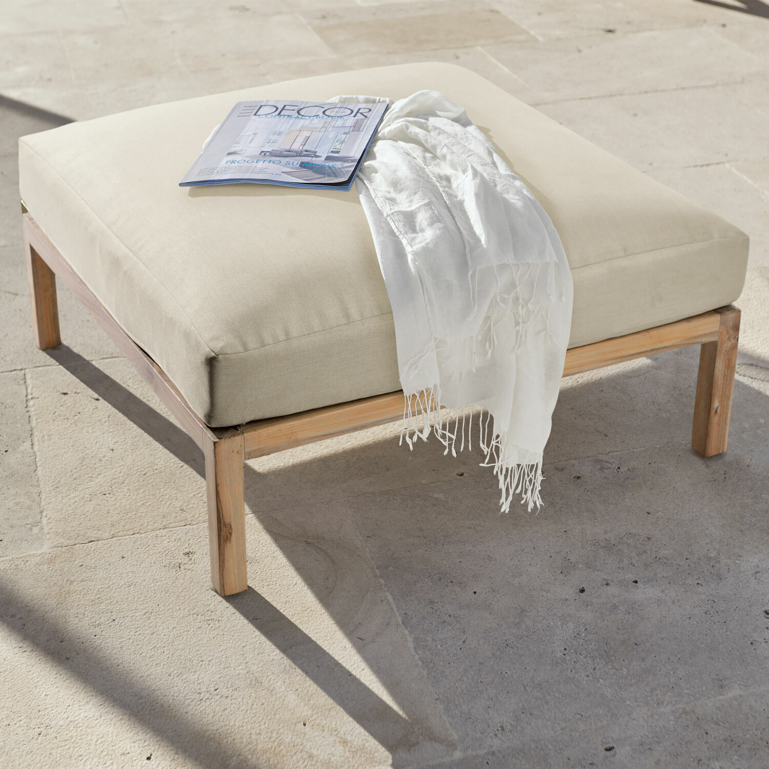 Reposapiés beige con estructura de madera y cojín suave, ideal para relajarse en el salón