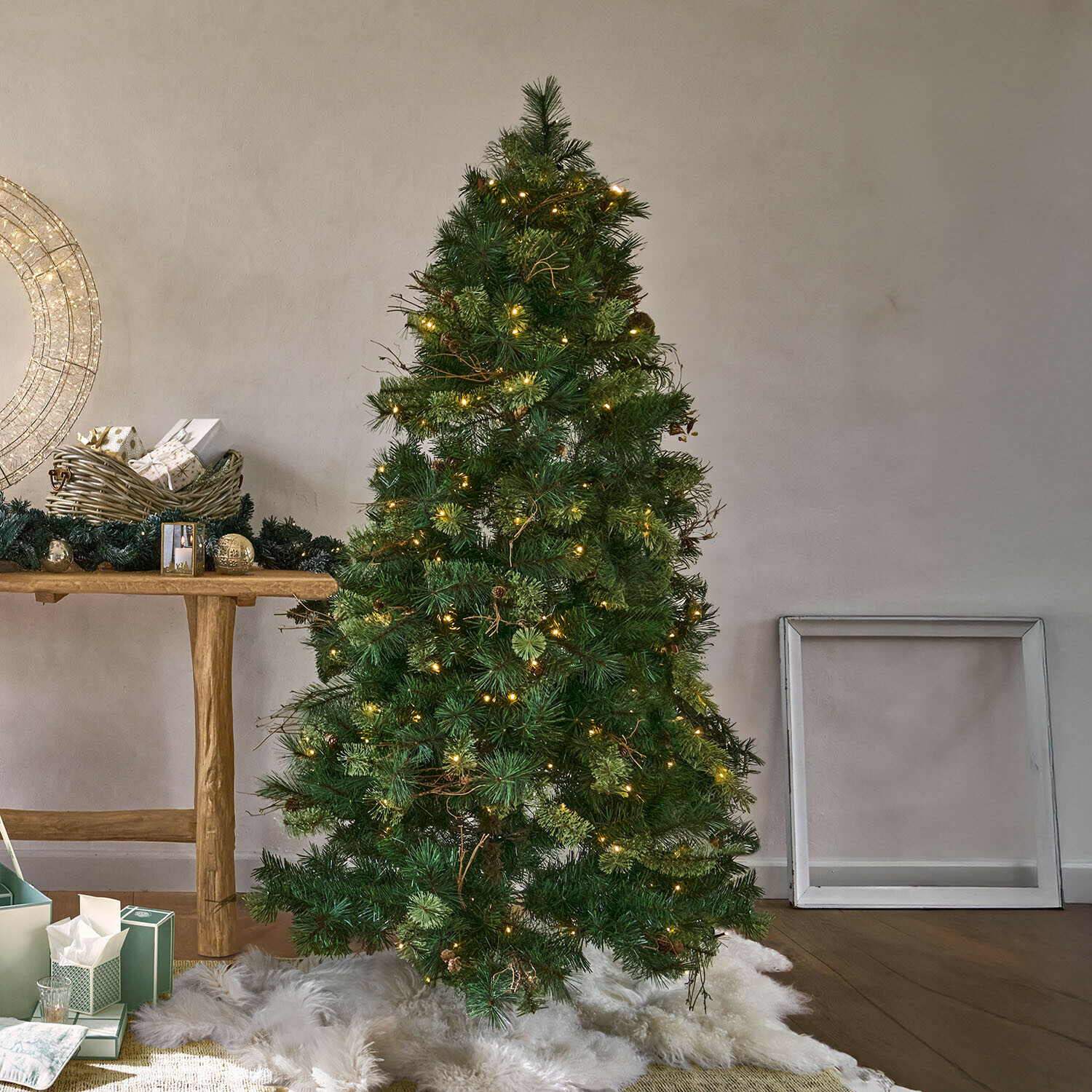 Árbol de Navidad LED Yundra Árbol de Navidad artificial verde con agujas y luces LED cálidas sobre alfombra blanca de piel sintética