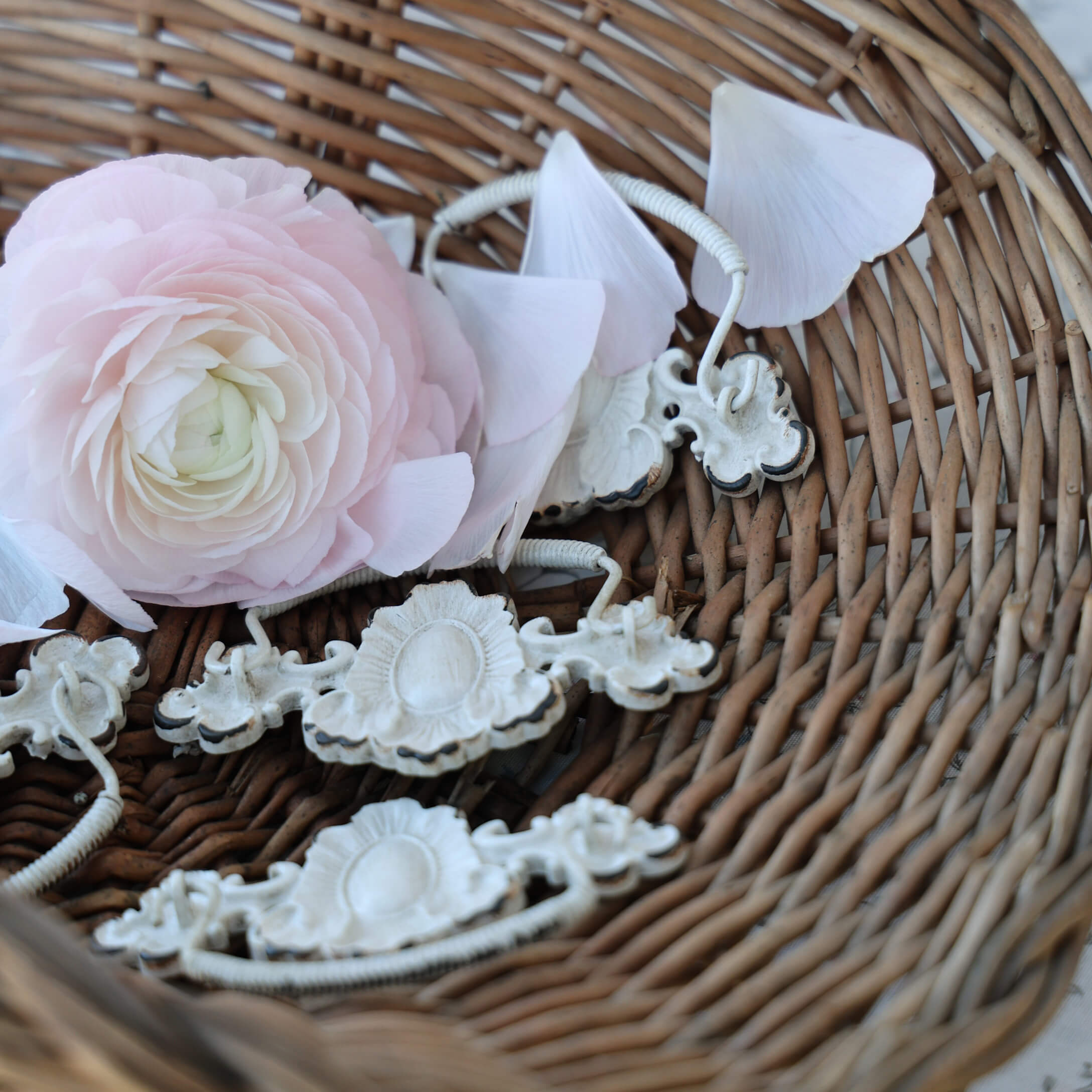 Flor rosa delicada y asas metálicas blancas en cesta de mimbre, decoración vintage para interiores