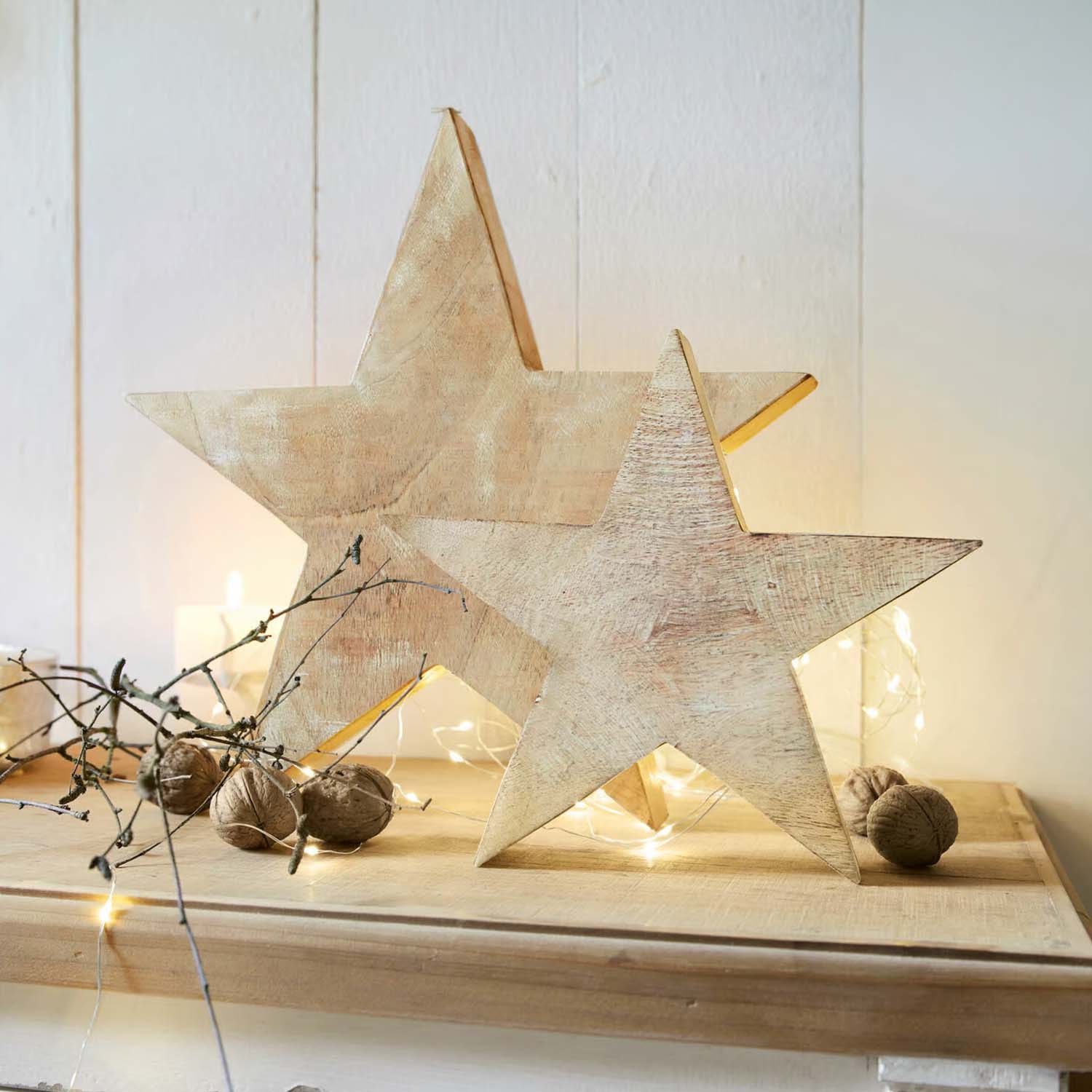 Decoraciones de madera en forma de estrellas color natural sobre mesa con nueces y luces LED