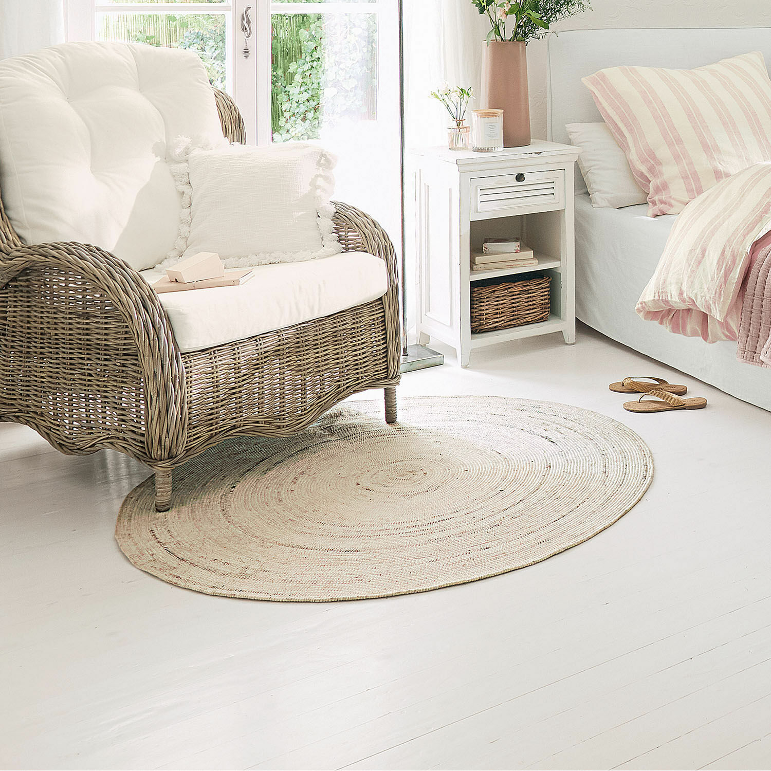Alfombra de interior y exterior Mommon Alfombra redonda de material natural color claro en sala acogedora con sofá de mimbre y cojines blancos