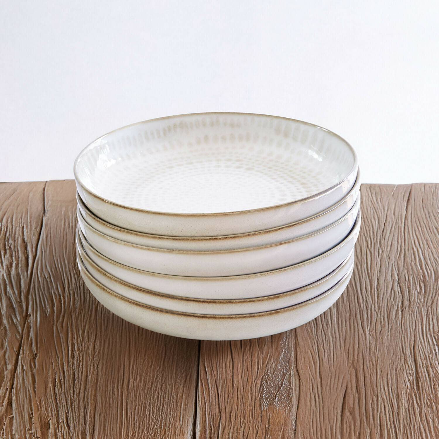 Set de 6 platos hondos Marnis Conjunto de cinco cuencos de cerámica crema con diseño sutil sobre mesa de madera