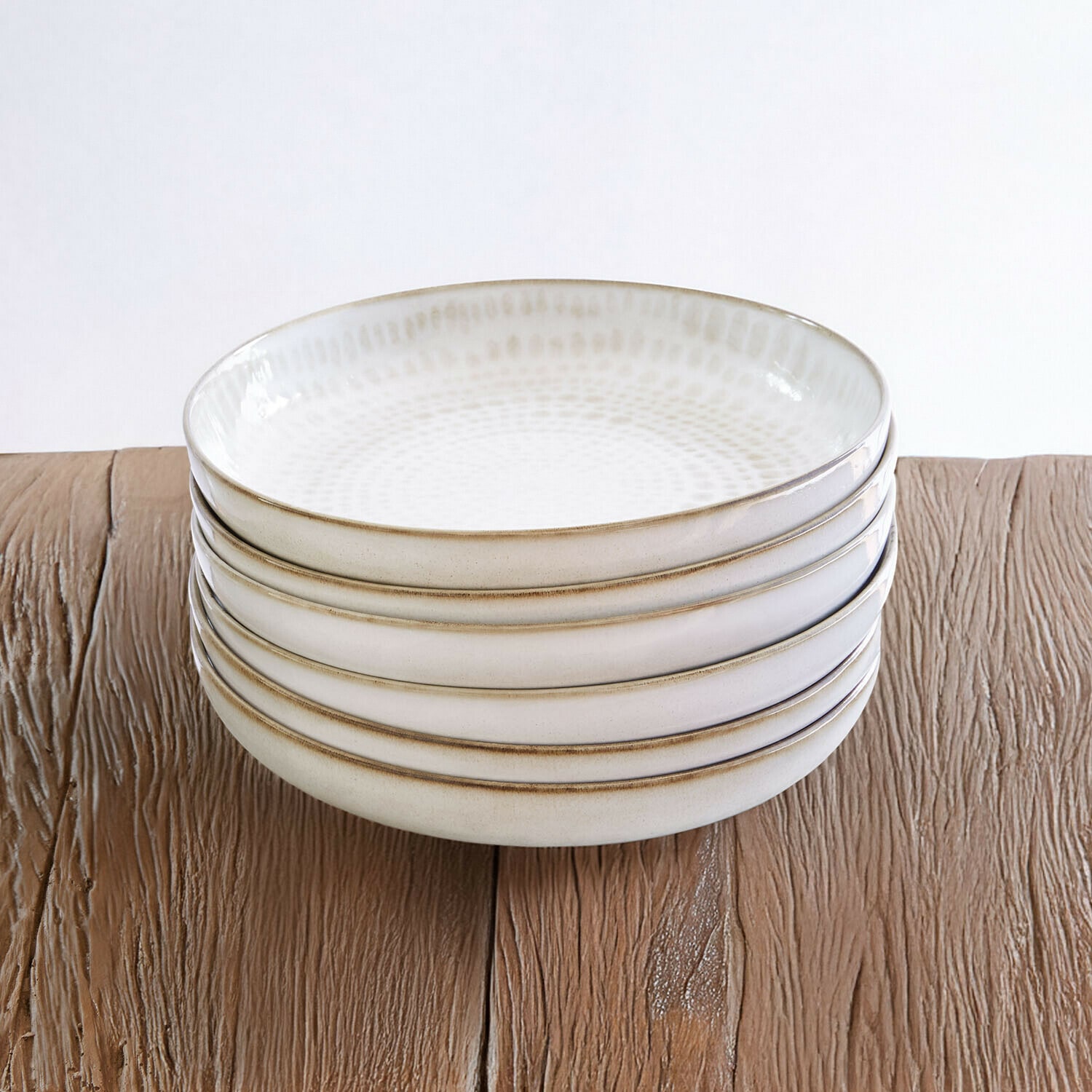 Set de 6 platos hondos Marnis Conjunto de cinco cuencos de cerámica crema con diseño sutil sobre mesa de madera