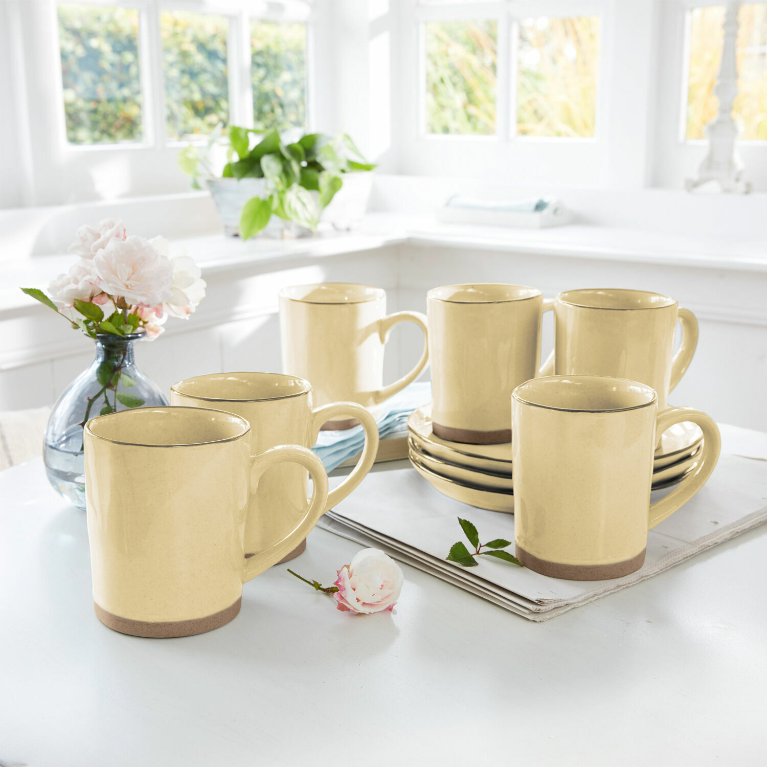 Set de 6 tazas Biarré Conjunto de seis tazas de cerámica amarilla con base marrón sobre mesa clara en cocina luminosa