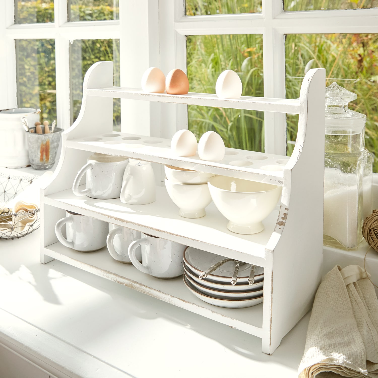 Estante de cocina de madera blanca con espacio para huevos, tazas y cuencos en cocina luminosa
