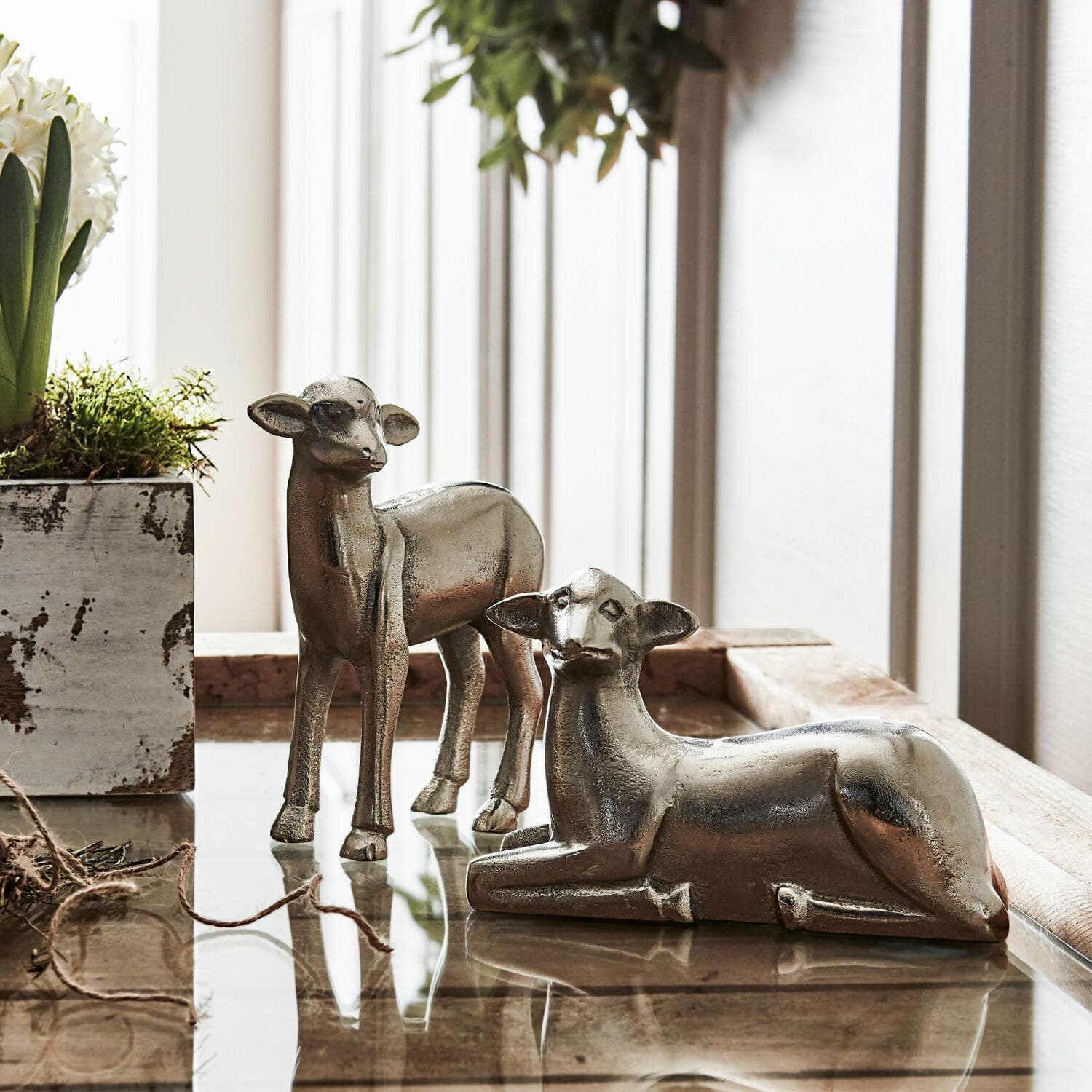 Set de 2 corderos decorativos Charmille Dos figuras de ciervos plateados de metal sobre mesa de cristal, decoración rústica para interiores
