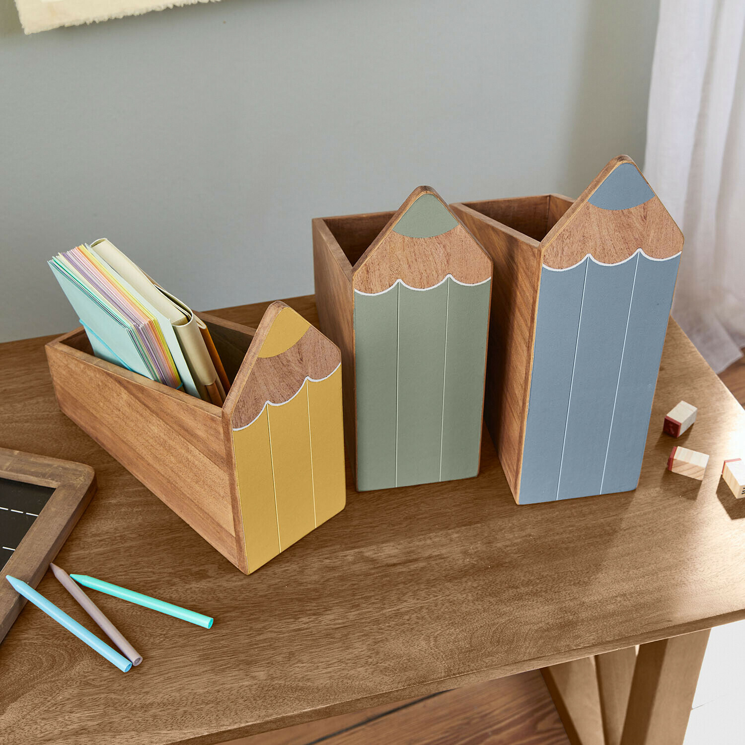 Set de 3 organizadores Sønvik Conjunto de tres organizadores de madera con forma de lápices en colores amarillo, verde y azul sobre escritorio de madera